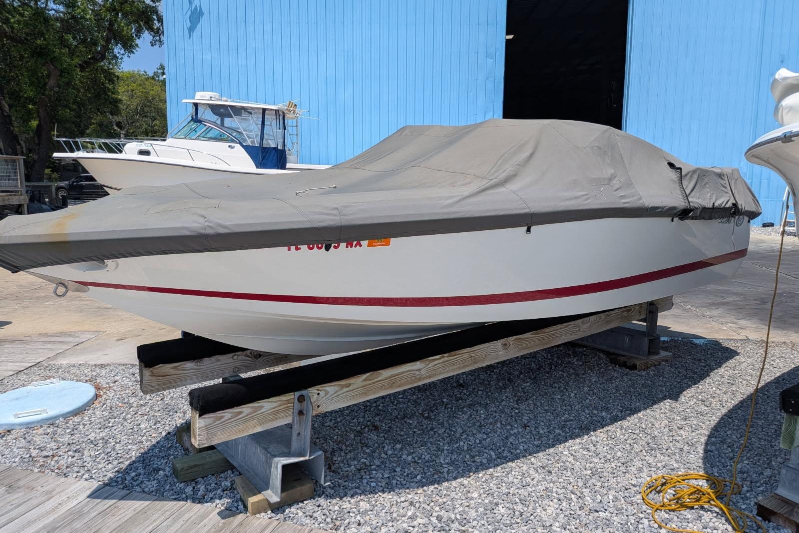 Covered 2020 Cobalt 206 boat on trailer, parked outdoors near a blue building.
