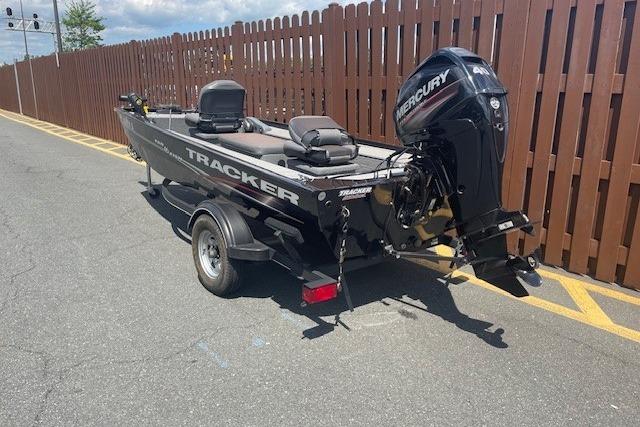 2019 Tracker Panfish 16 boat with Mercury engine on trailer, parked near wooden fence.