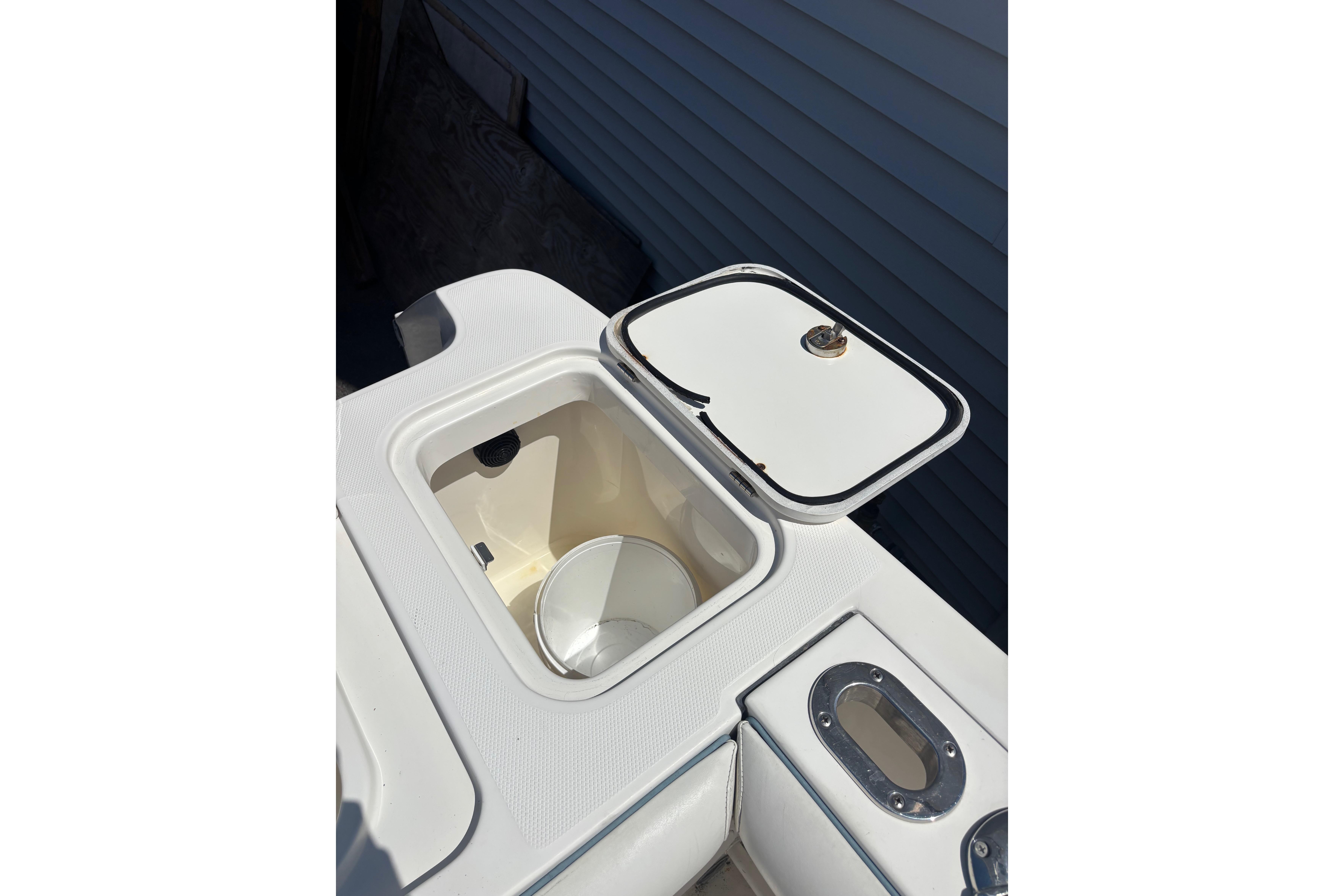 Open storage compartment on a 2006 Edgewater 318CC boat, featuring a white lid and interior.