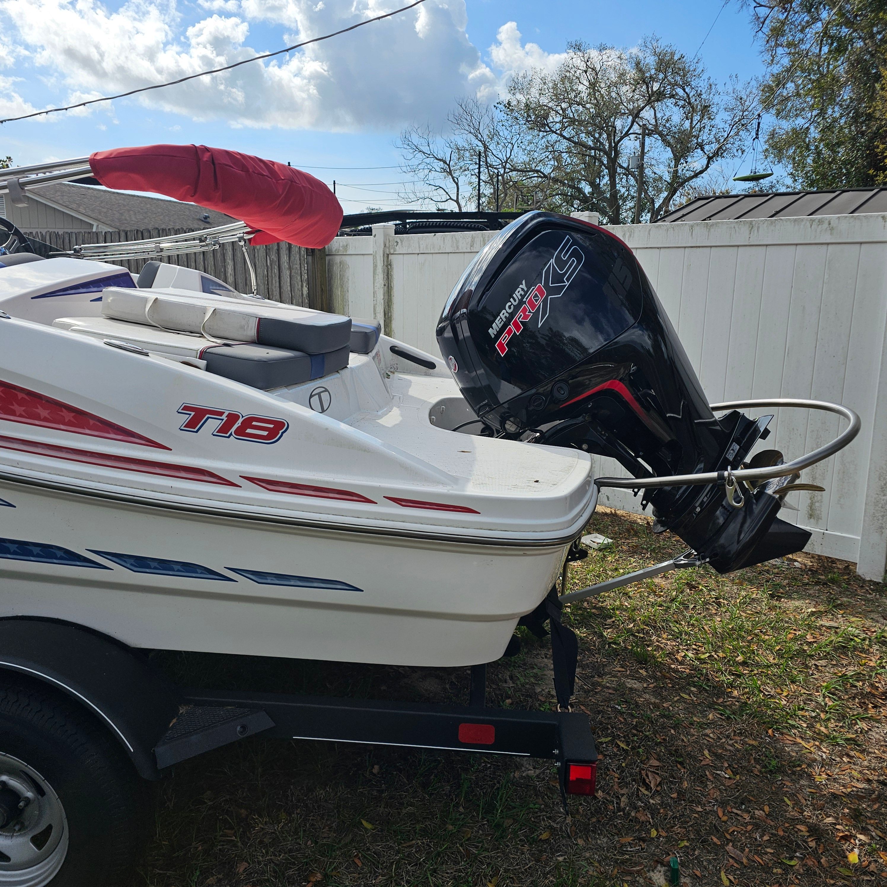 2024 Tahoe T18 boat with Mercury engine, parked on trailer, under blue sky.