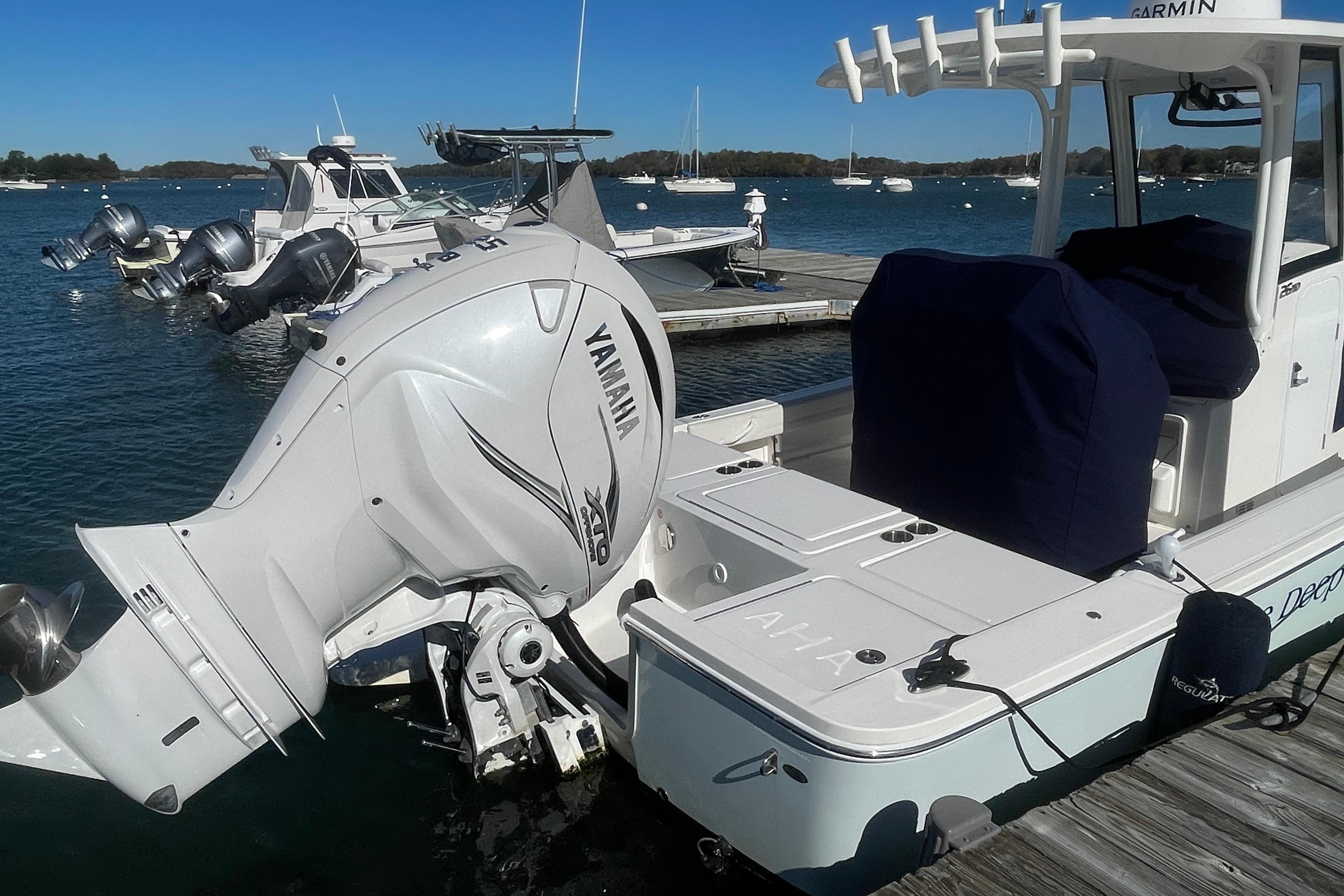 2023 Regulator 26XO boat docked with Yamaha outboard motor, clear blue water background.