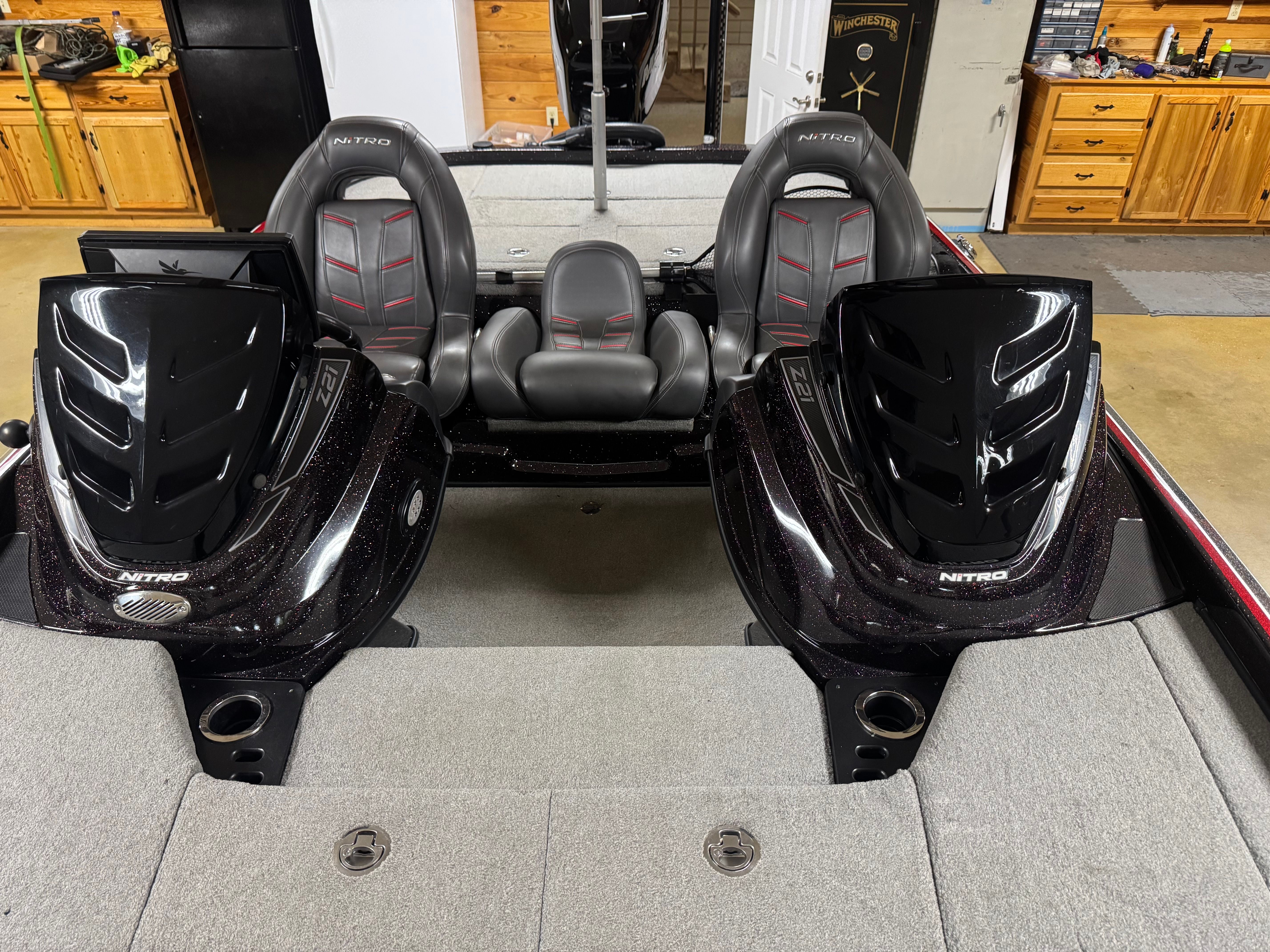A Nitro Z21 boat with dual engines and gray seats in a garage.
