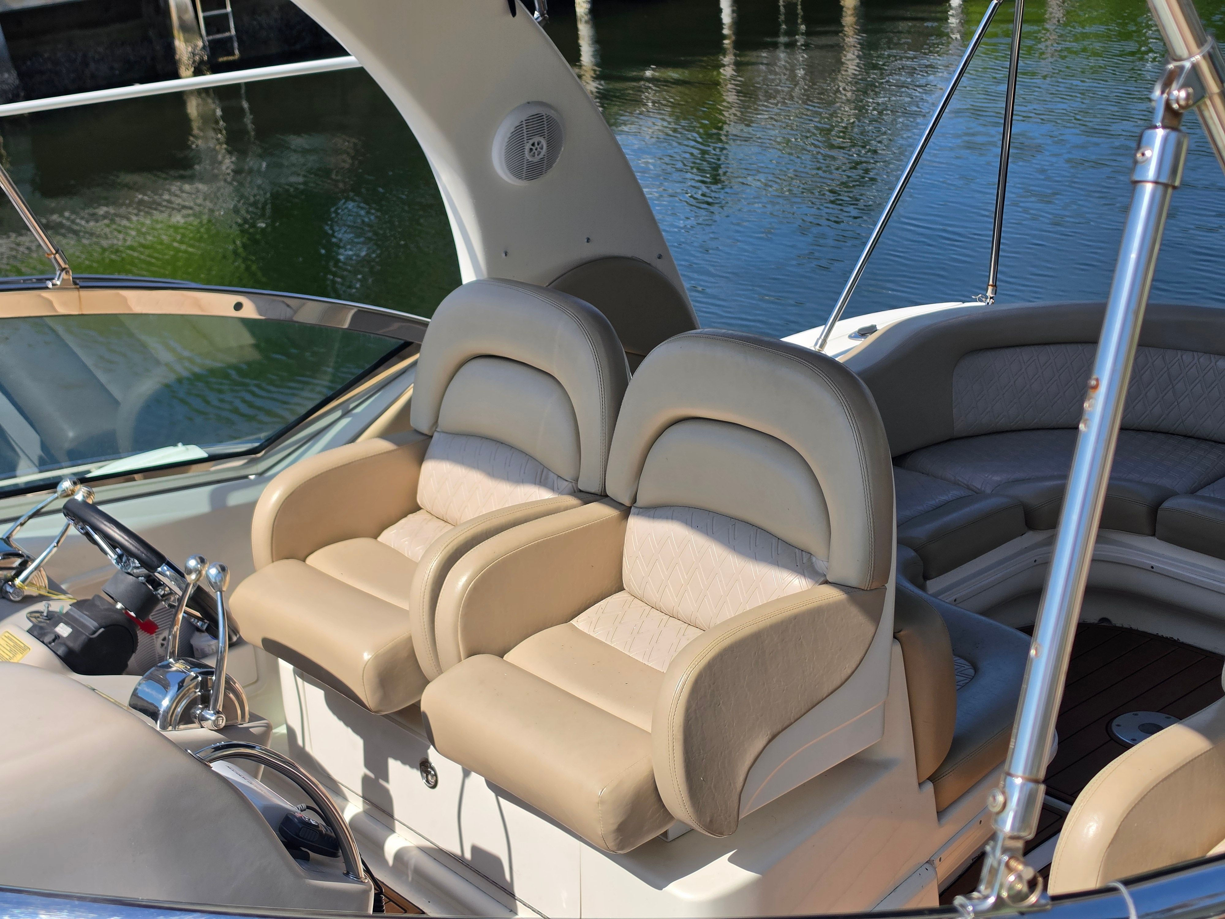 Two beige leather seats on a boat overlooking the water.