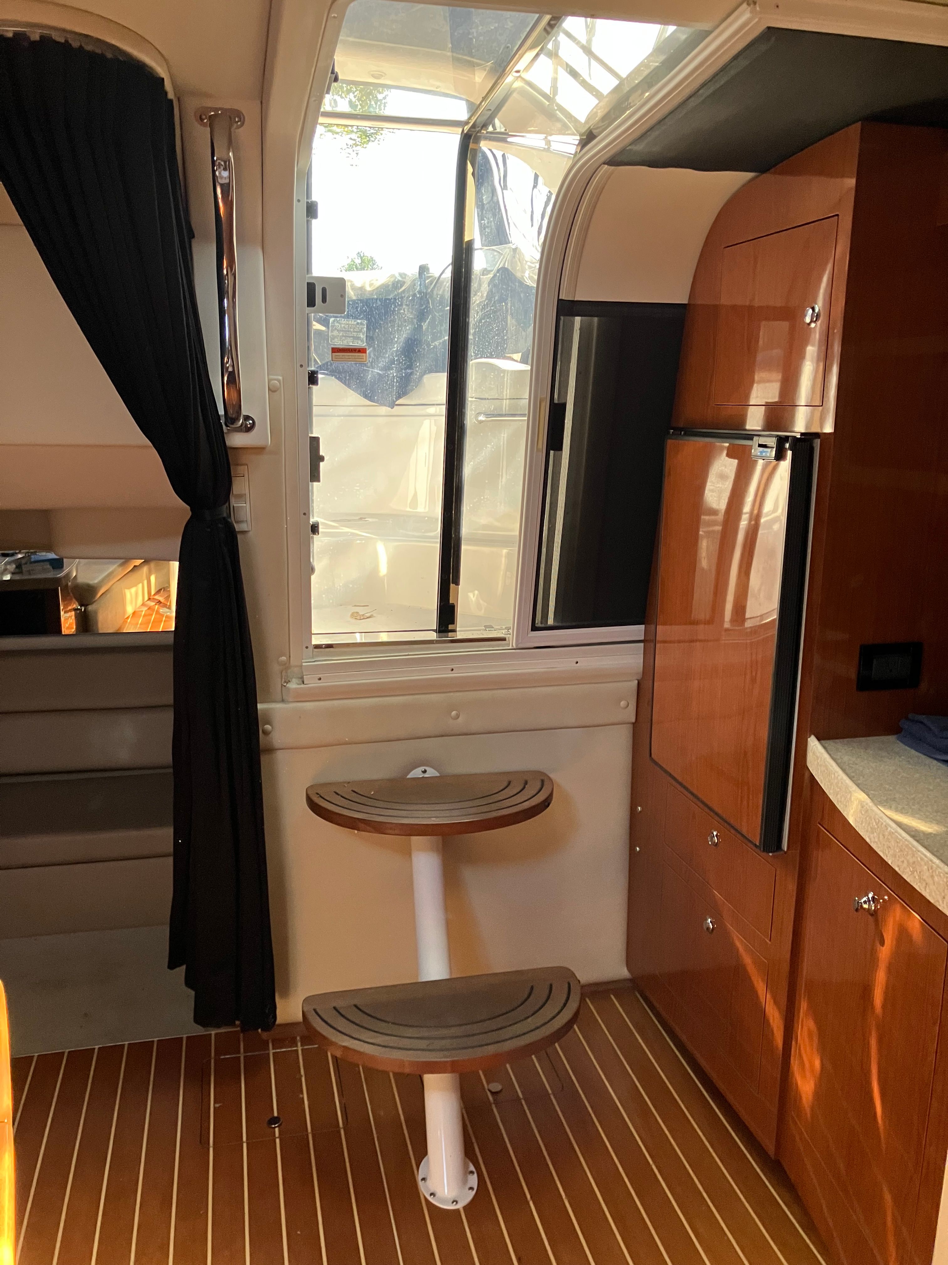 Interior of 2008 Custom Commodore with wooden steps and refrigerator.