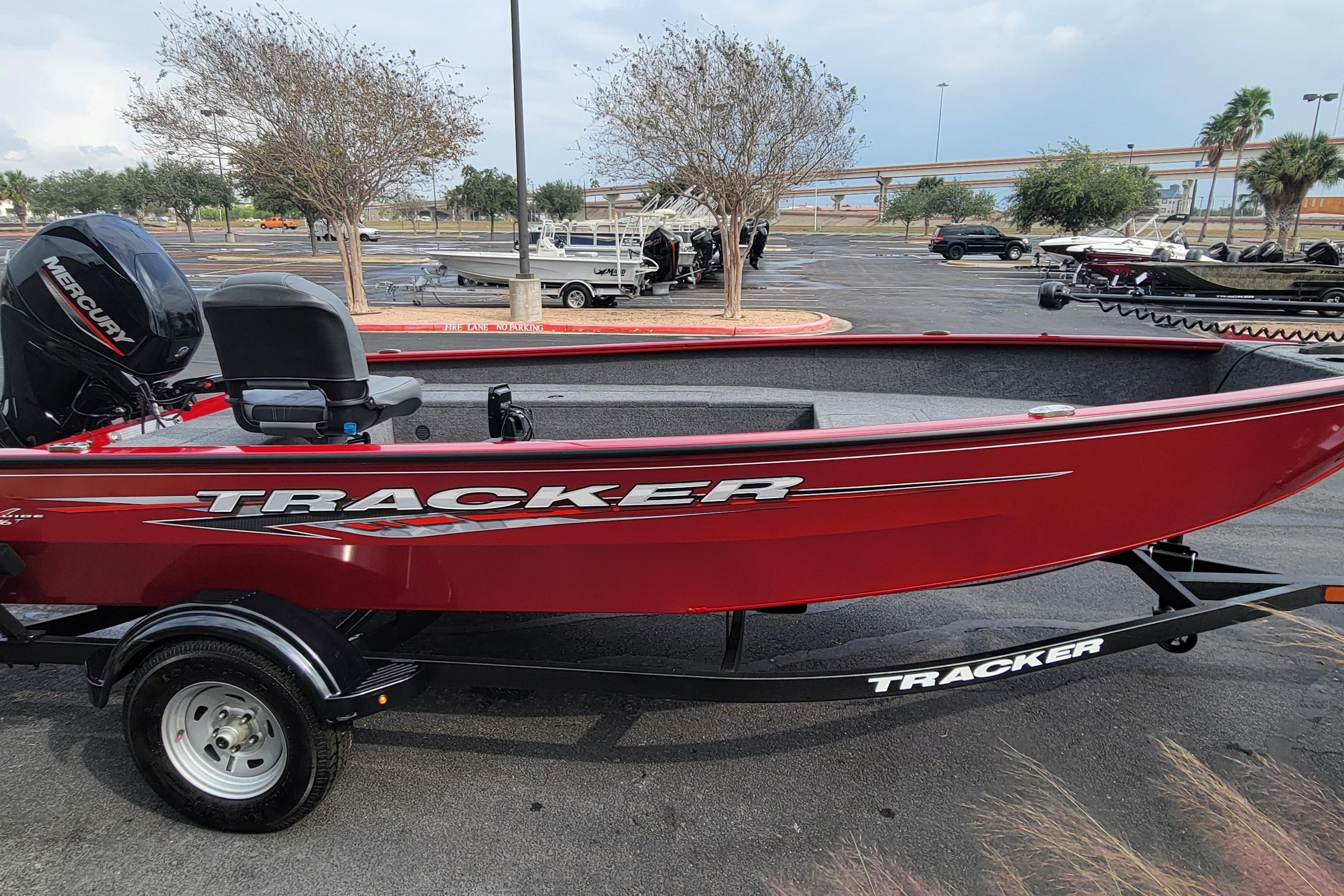 Red 2025 Tracker Super Guide V-16 T boat on trailer, parked outdoors.