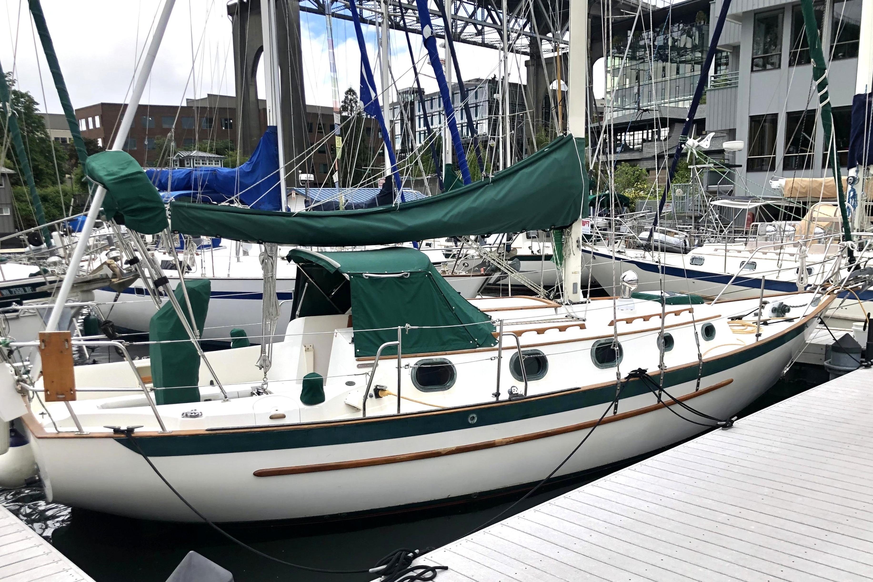 1988 Pacific Seacraft 31 sailboat docked at marina, featuring green covers and classic design.