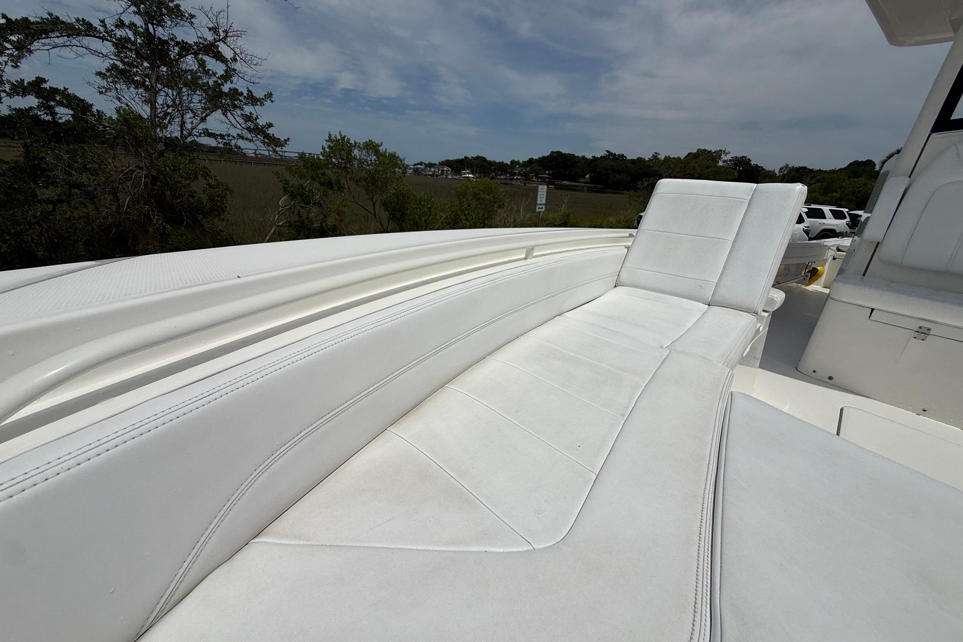 2019 Regulator 26XO boat with white cushioned seating, surrounded by trees and parked cars.
