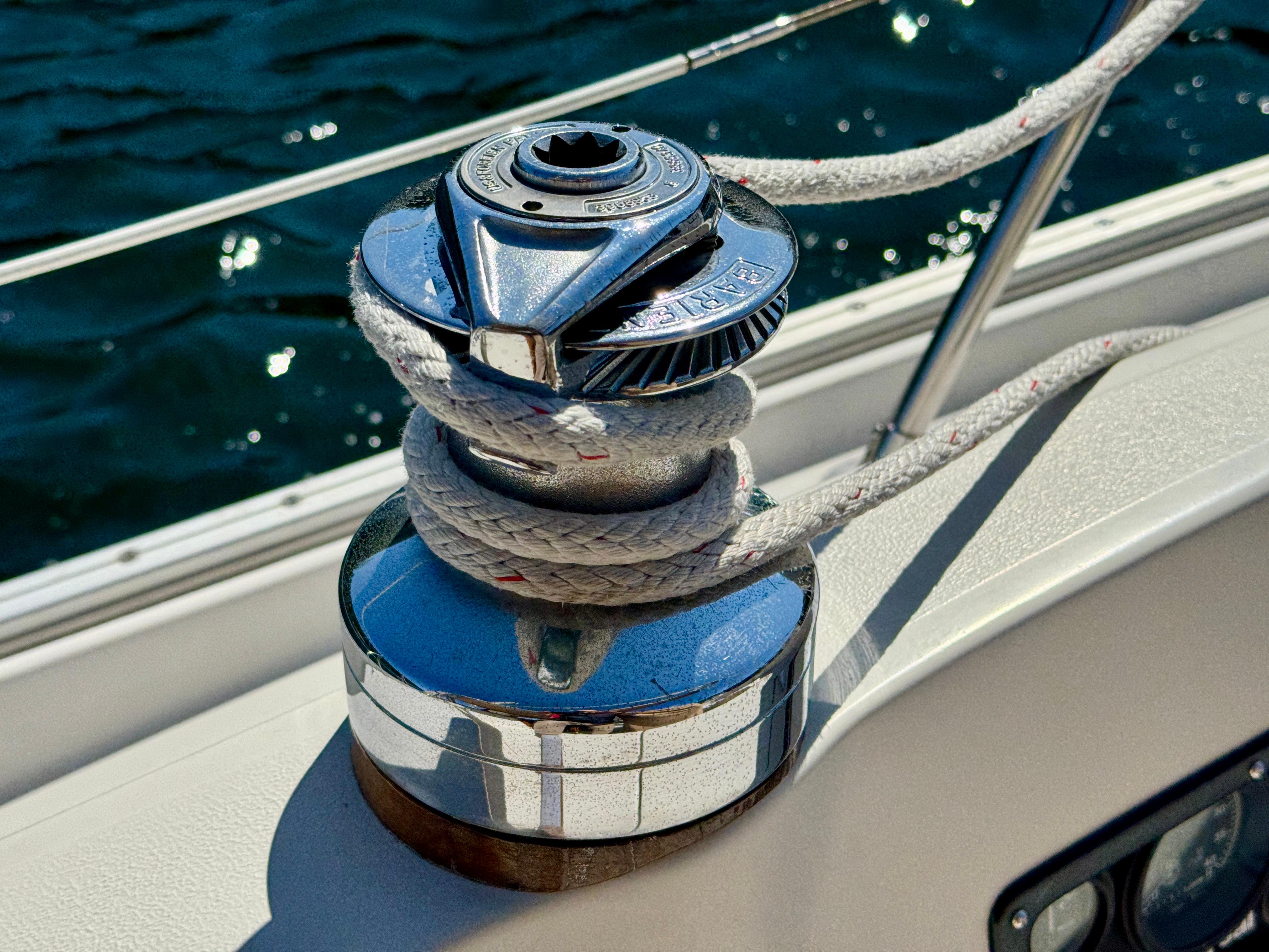 Winch on 1989 Nonsuch 30 Ultra sailboat with rope, against a backdrop of water.