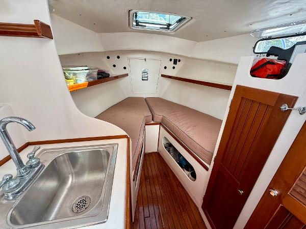 1978 Dyer 29 Trunk Cabin interior with sink, wooden flooring, and cozy sleeping area.
