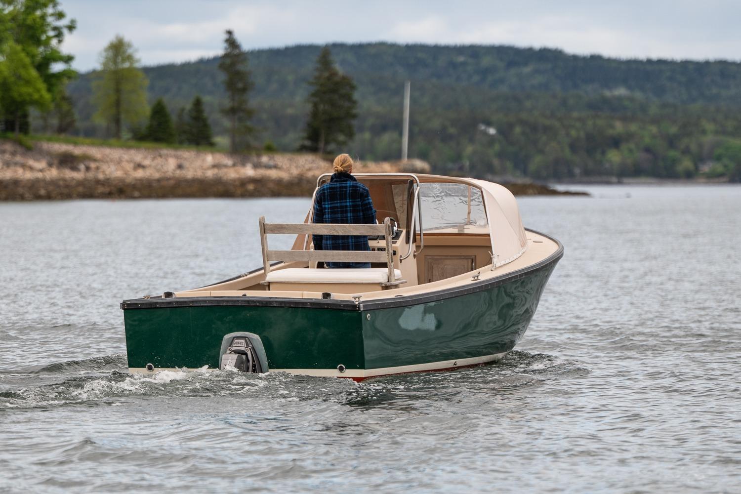 1989 Ellis 24 Open boat cruising on a scenic lake with lush green hills.