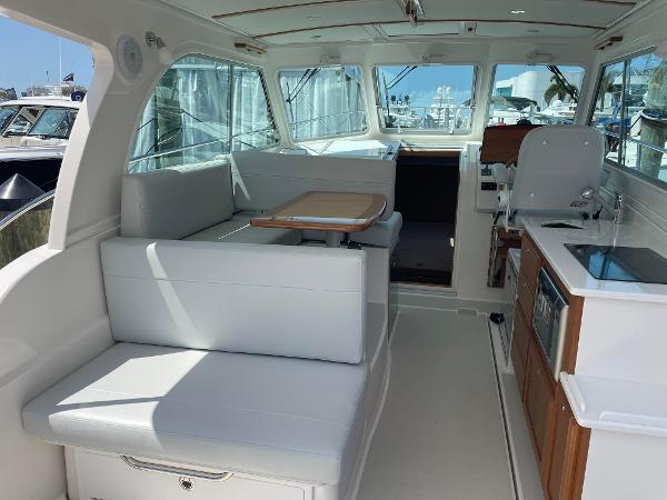 Interior of 2024 Back Cove 34O boat with white seating, dining table, and kitchenette.