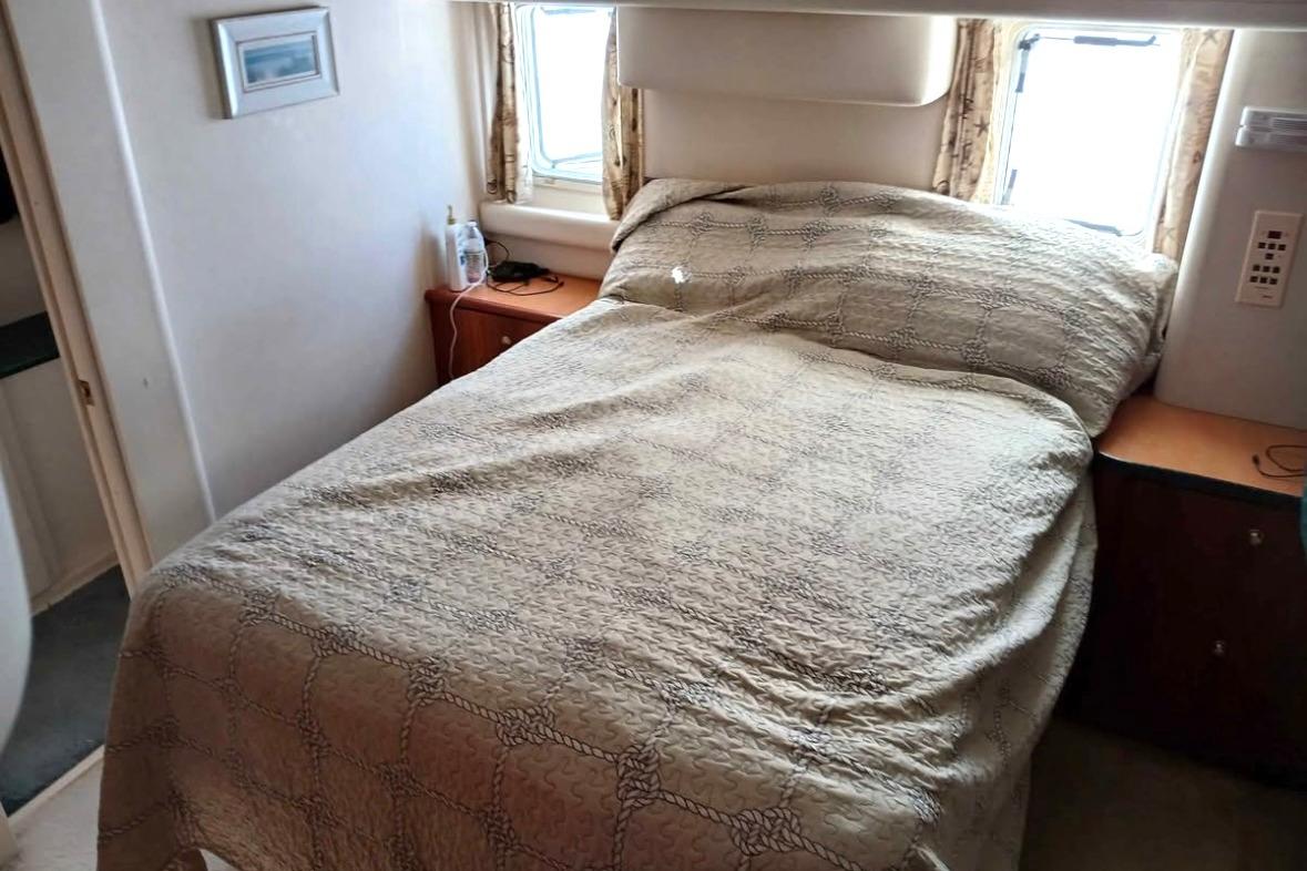 Cozy bedroom interior of 2000 Silverton 422 Motor Yacht with bed and window view.
