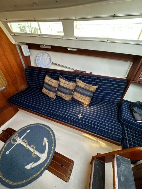 Interior of a 1985 Catalina 27 with blue seating and anchor-themed rug.