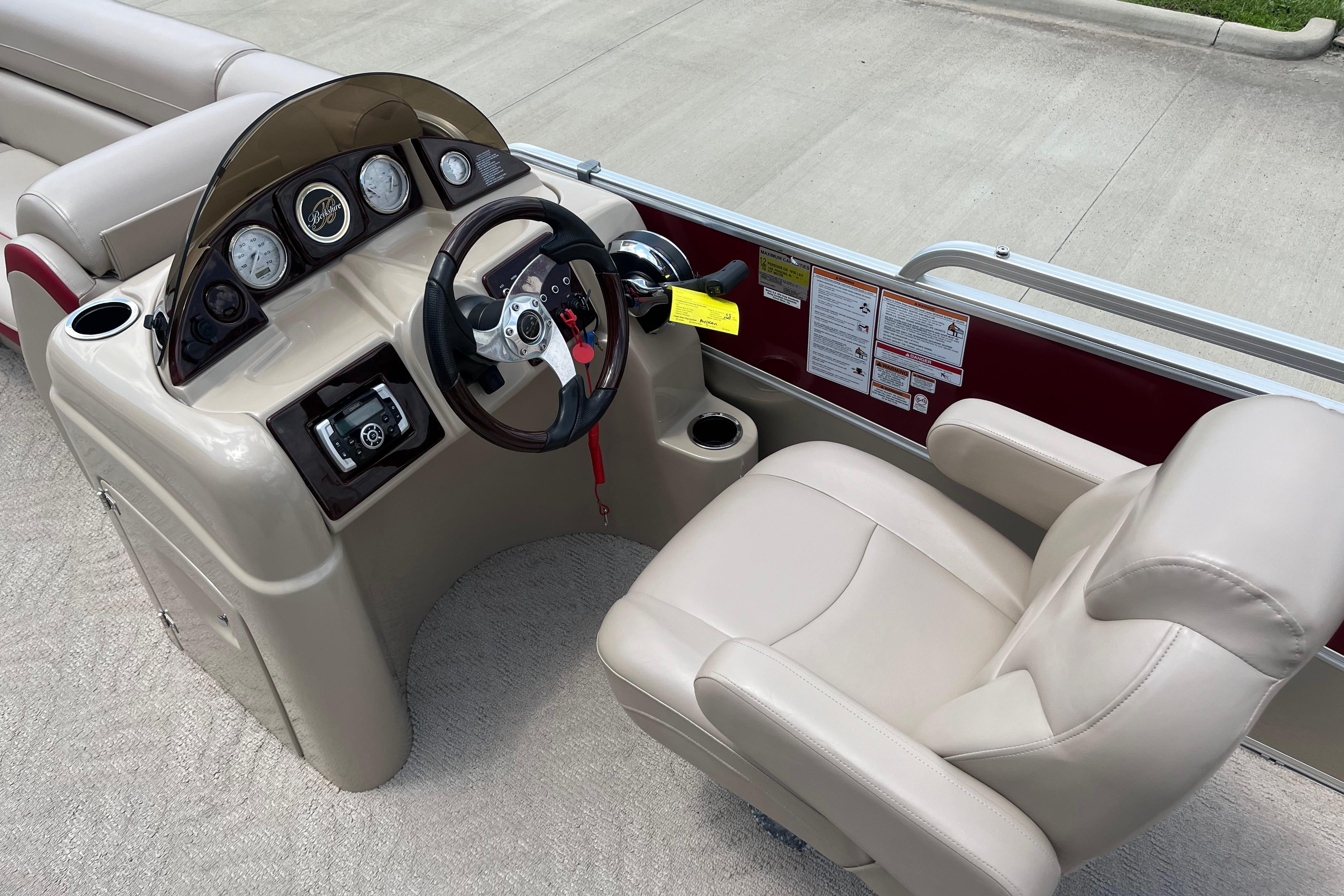 2013 Berkshire 230CL CTS boat dashboard with steering wheel and beige captain's chair.