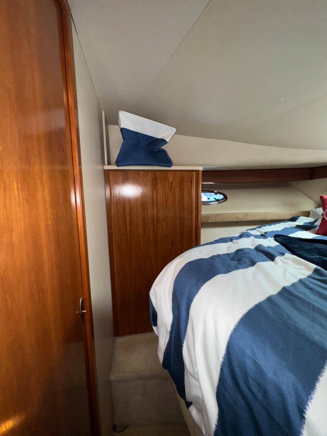 2003 Meridian 381 Sedan cabin interior with wood paneling and striped bedding.