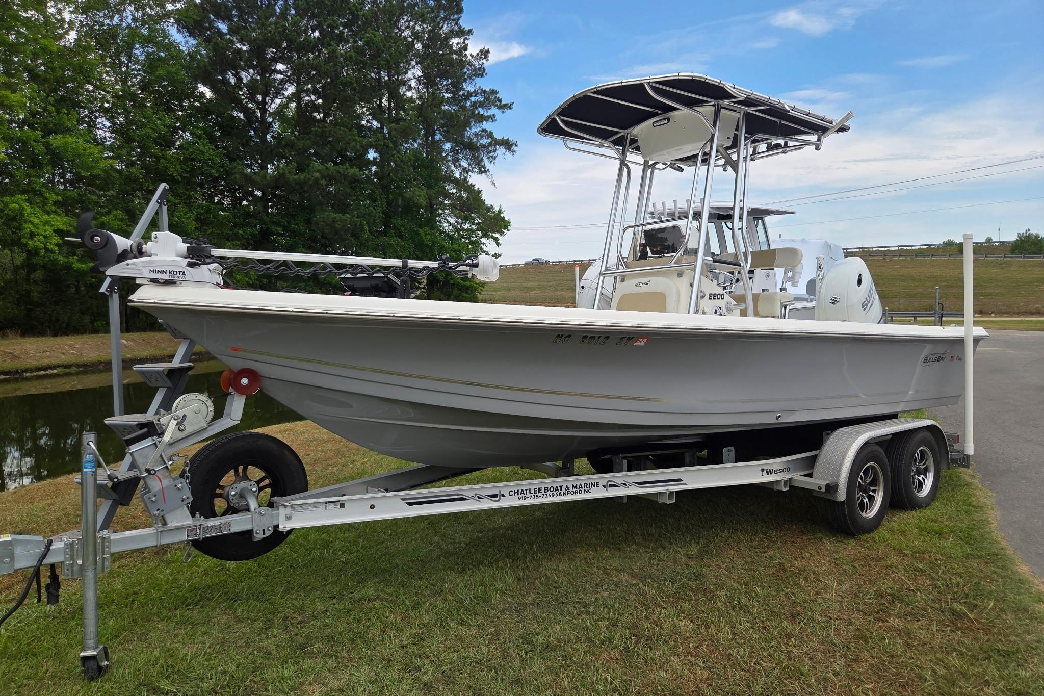 2023 Bulls Bay 2200 boat on trailer, parked on grass near waterway.