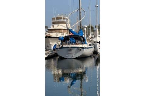 1983 Nonsuch 36 sailboat docked in a marina, reflecting on calm water.