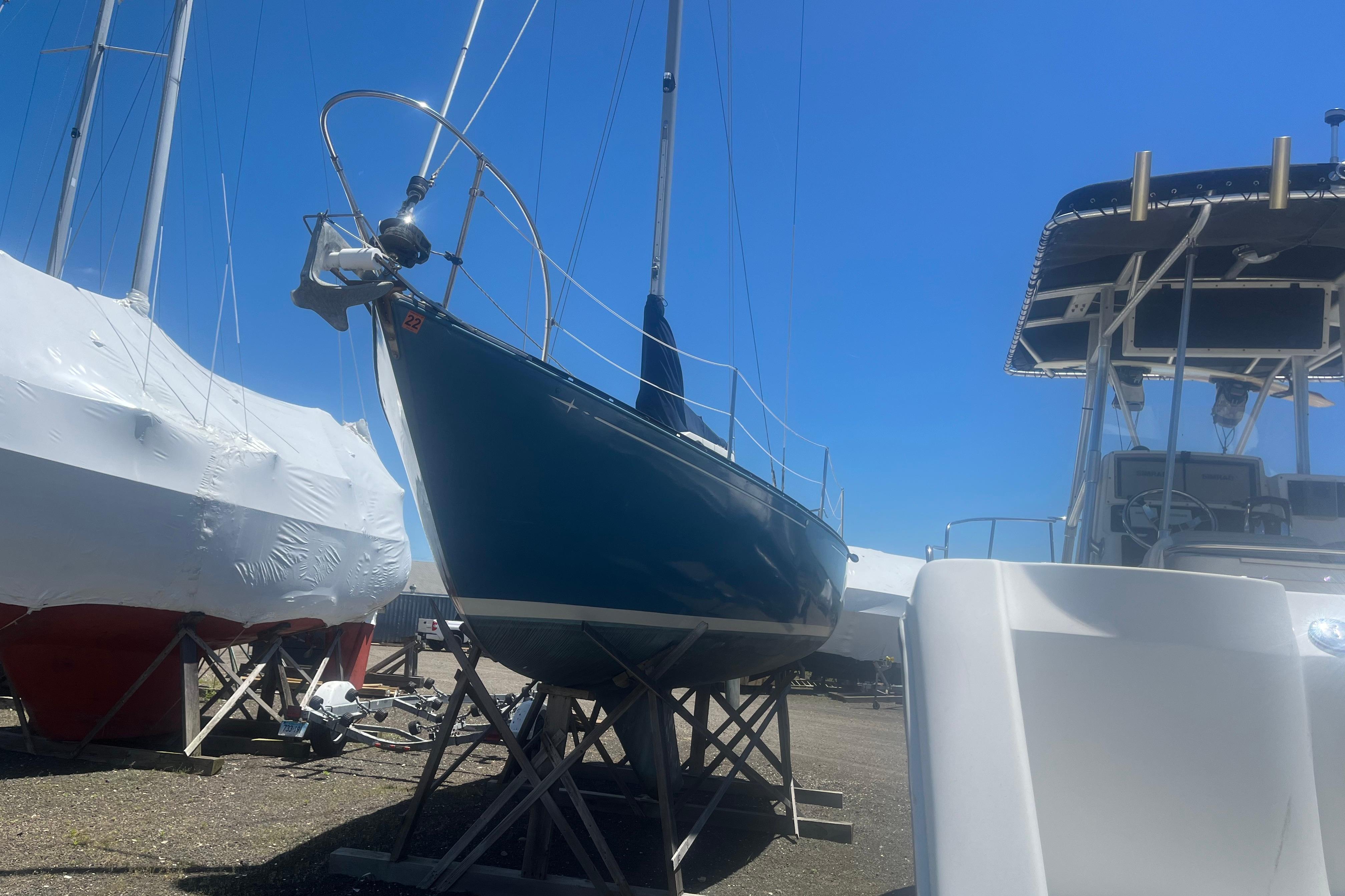 1972 C&C 30 sailboat on stands in a boatyard under clear blue sky.