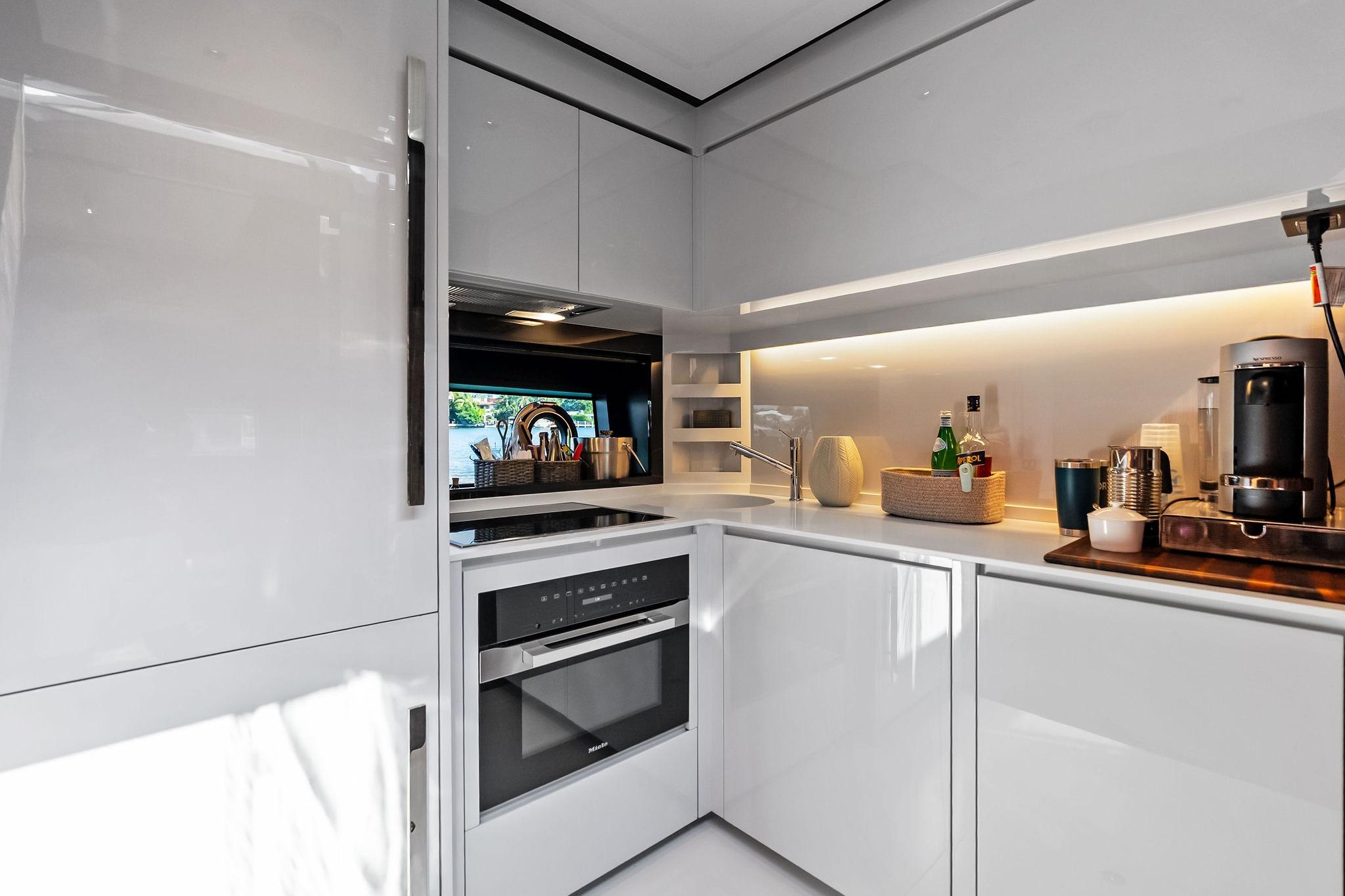 Modern kitchen interior on 2023 Riva 76 PERSEO Super yacht, featuring sleek white cabinetry and appliances.
