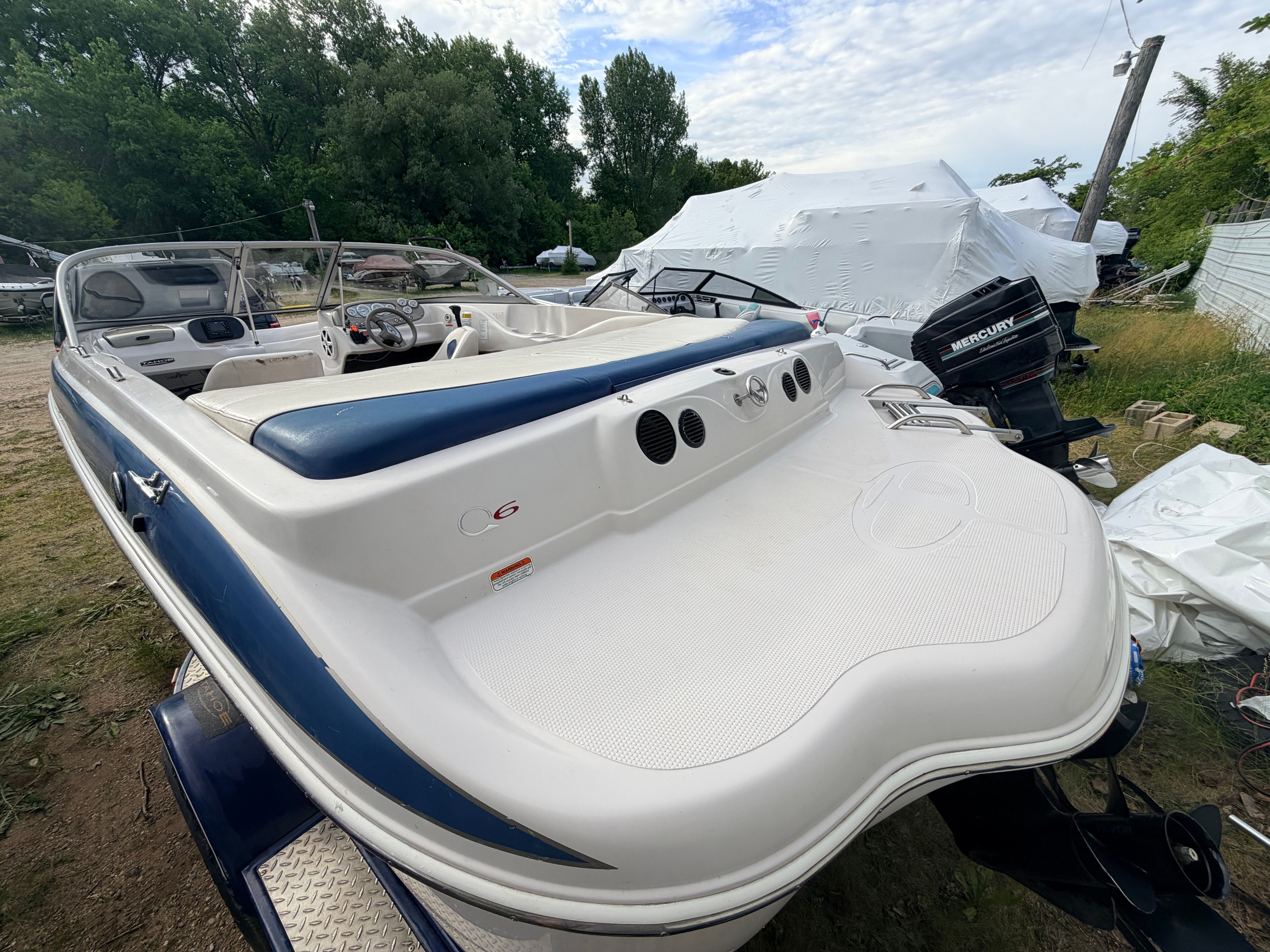 A 2005 Tahoe Q6 Sport boat on land. It features a blue and white design with a spacious sun deck.