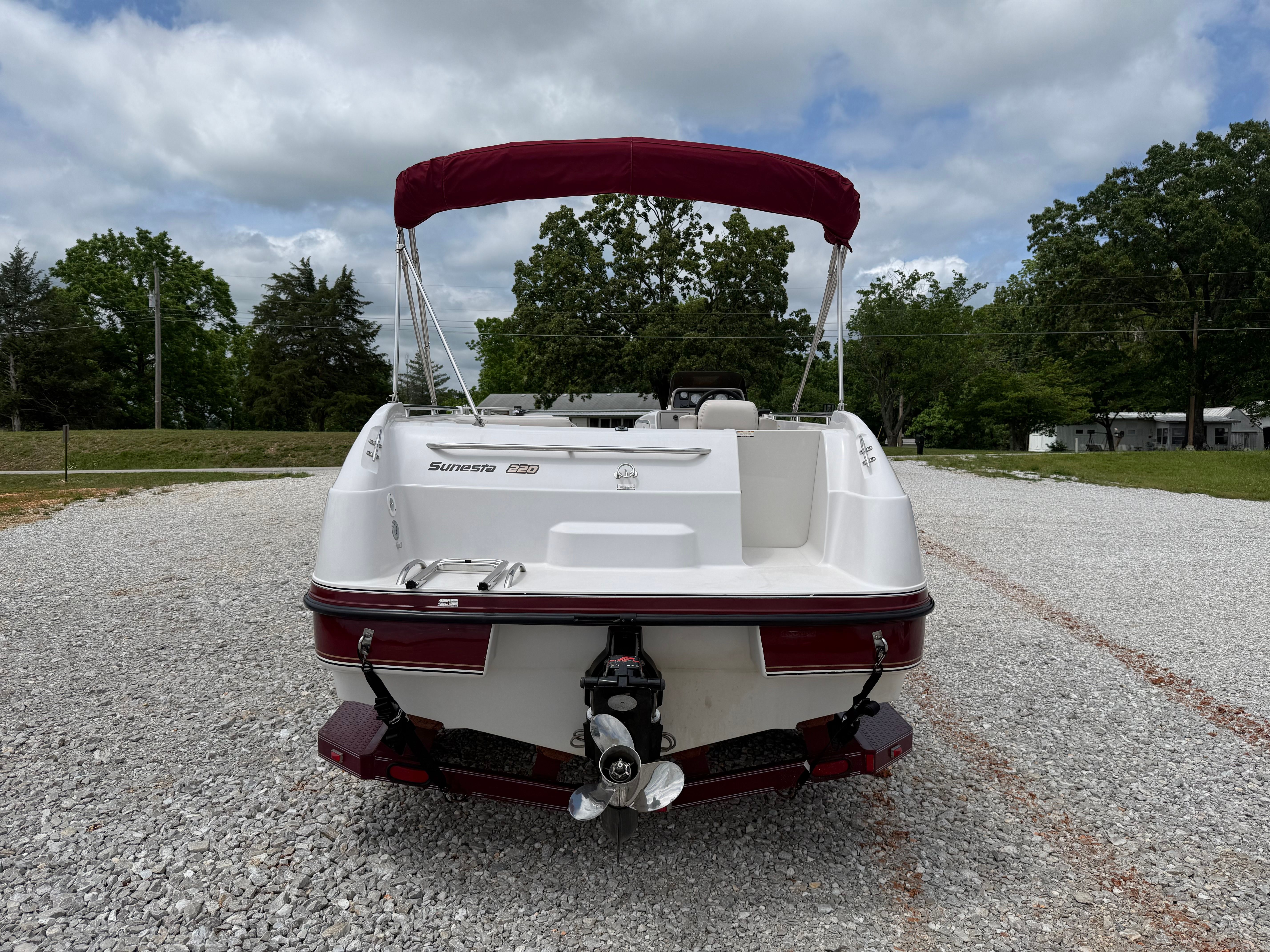 A 1994 Chaparral Sunesta 220 on a gravel lot. It features a red sunshade.