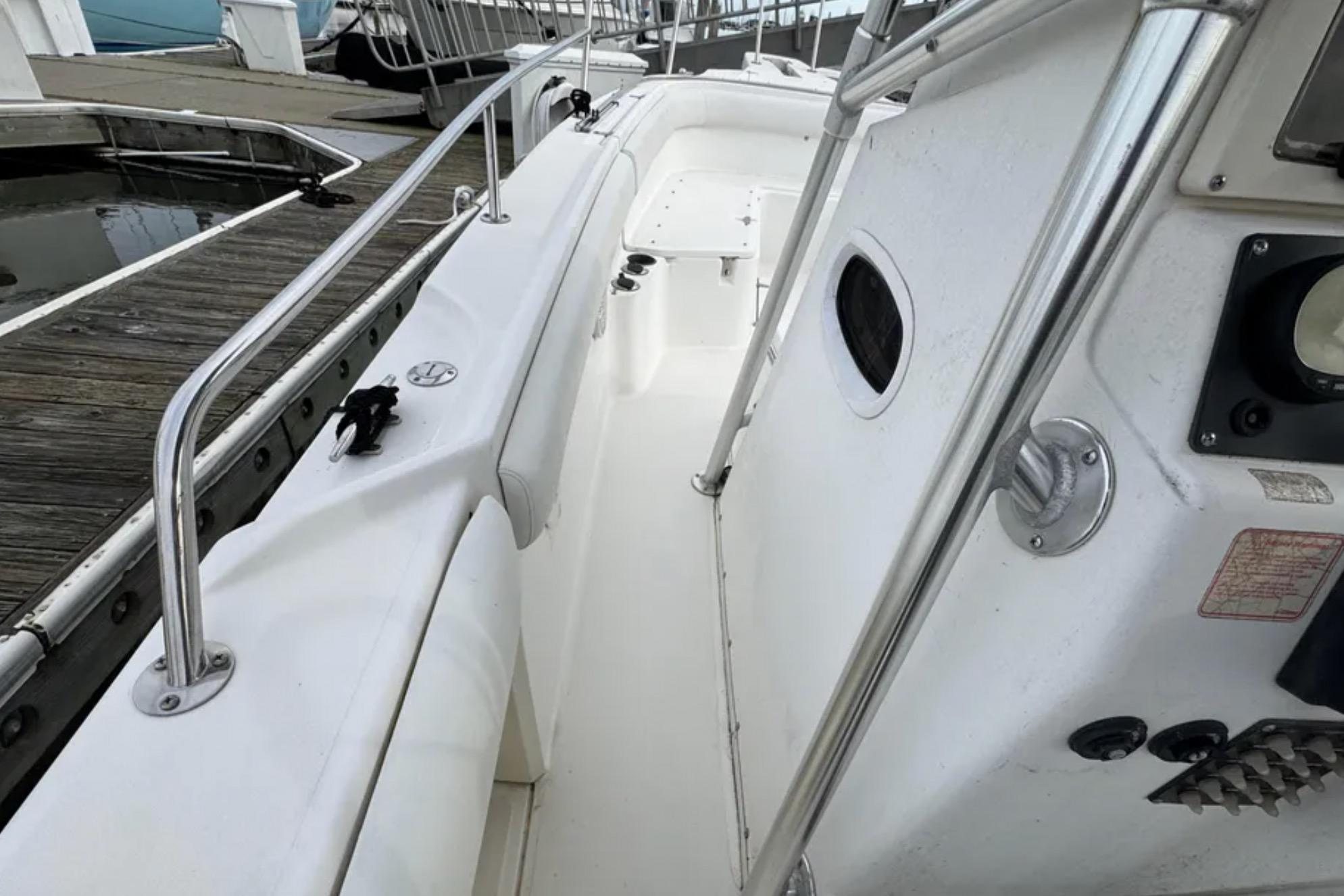 2001 Boston Whaler 26 Outrage boat docked, showcasing sleek white deck and railing.
