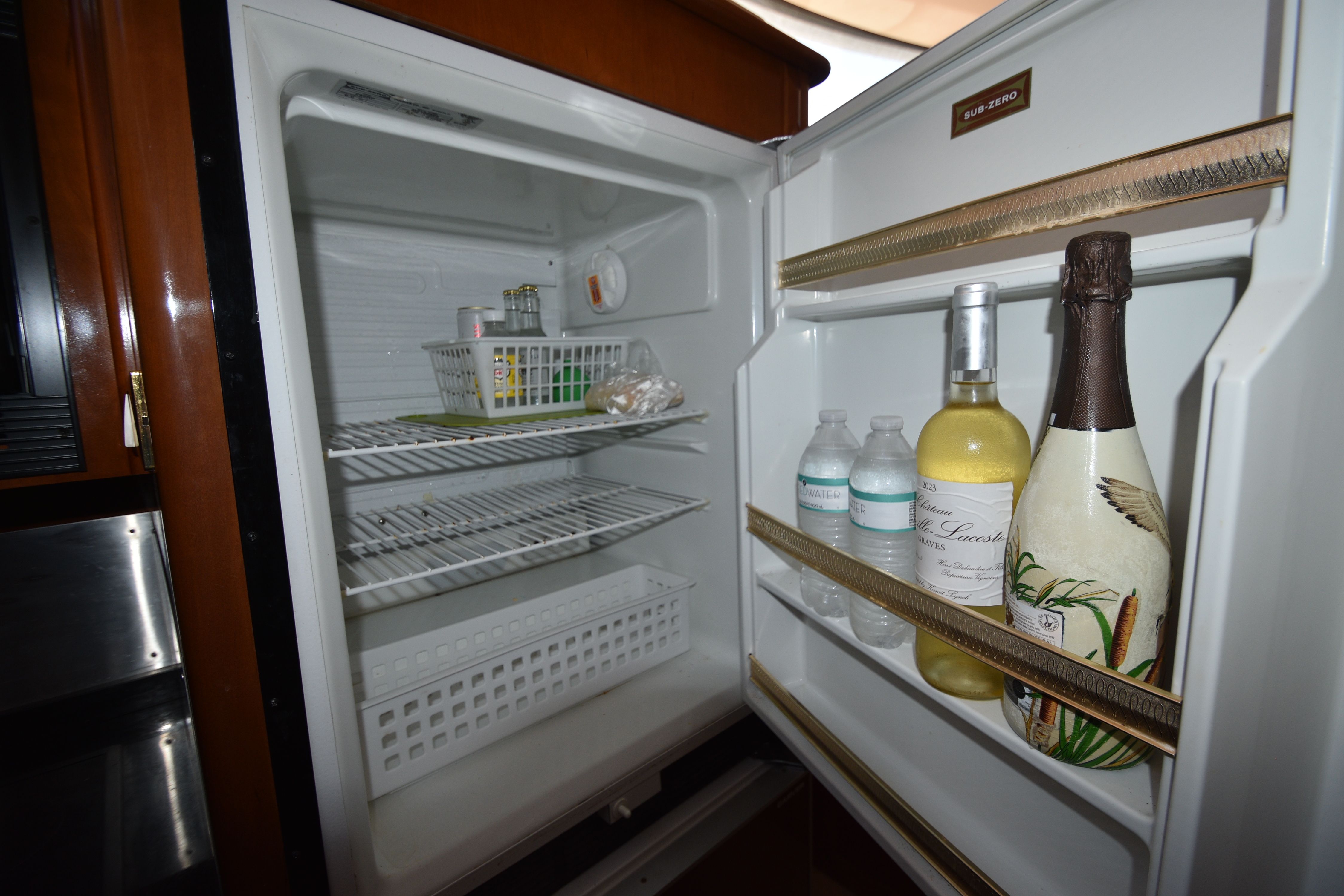 An open fridge with drinks and food in a yacht kitchen.