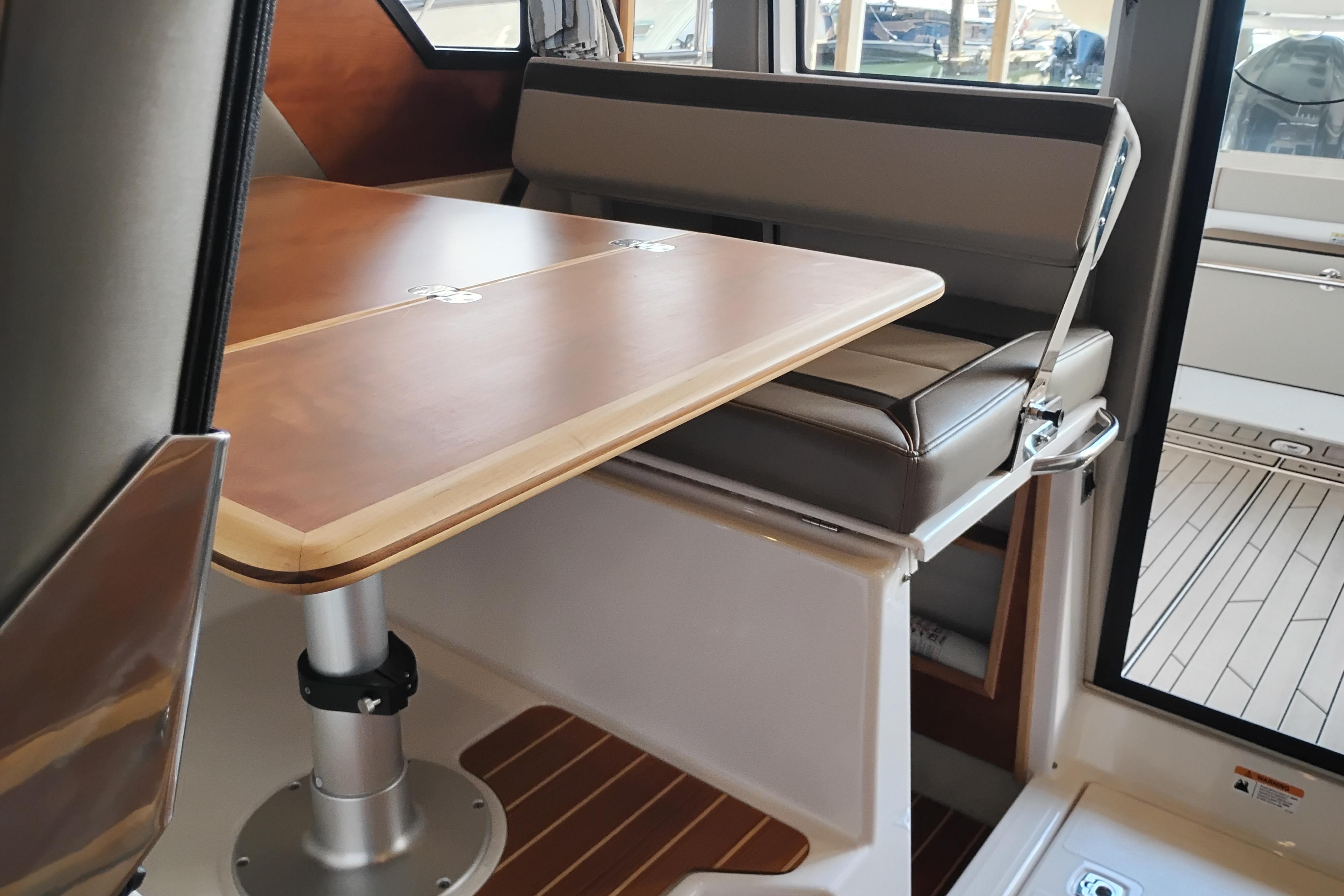 Interior of 2022 Cutwater C-32 Coupe featuring a wooden table and cushioned seating.