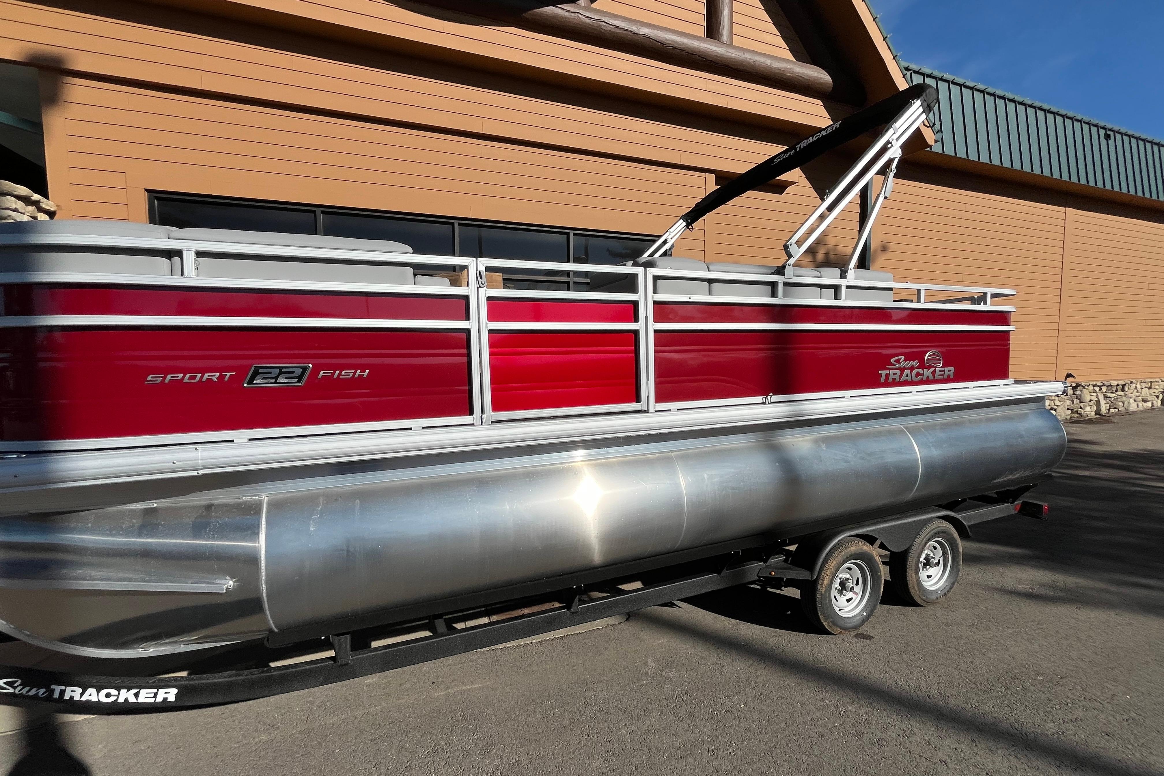 2026 Sun Tracker SportFish 22 XP3 pontoon boat on trailer, red and silver design.