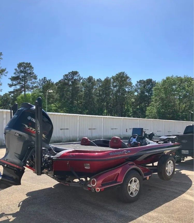 2013 Ranger Z519 boat on a trailer, surrounded by trees and a clear blue sky.