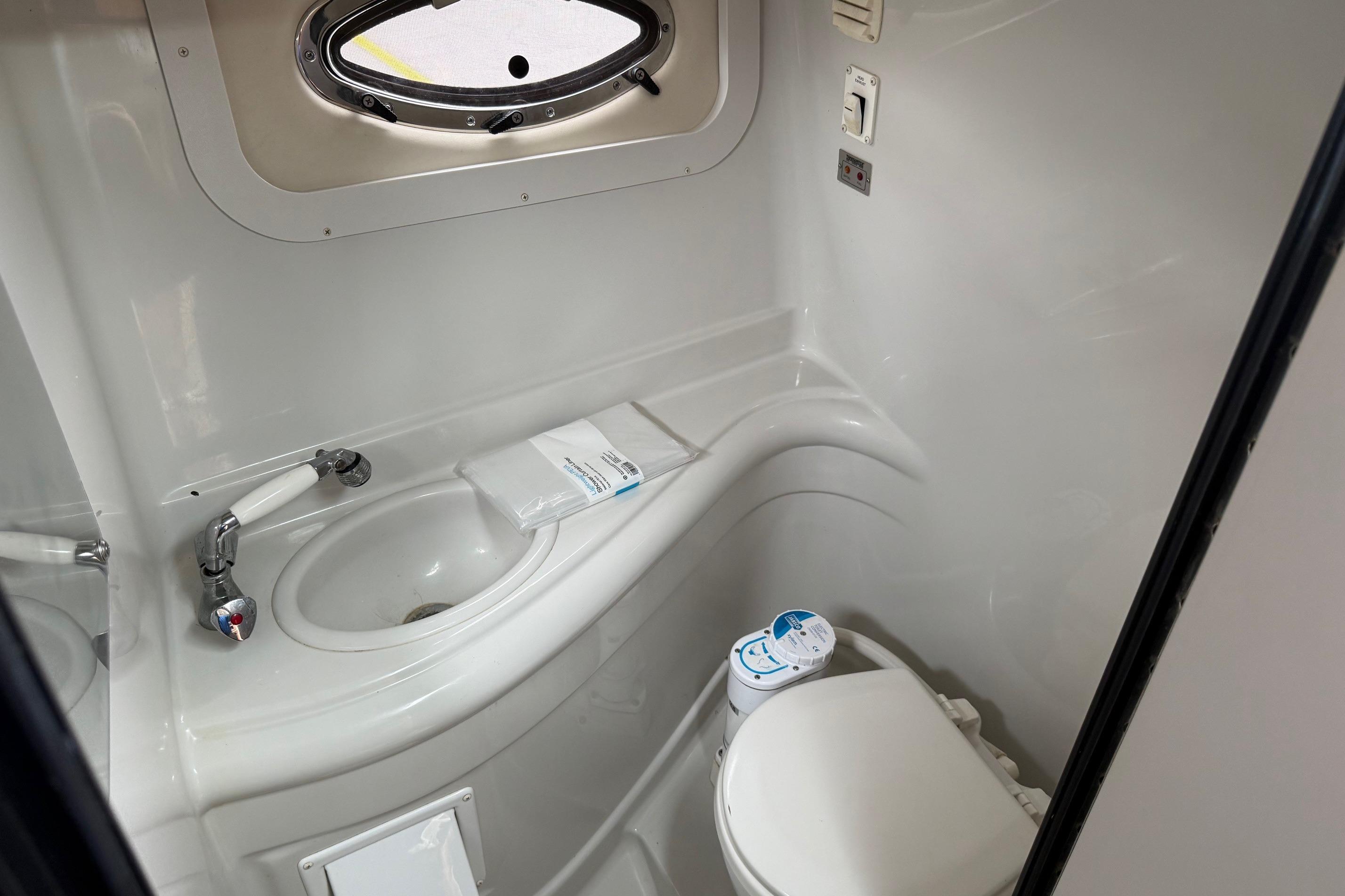 2005 Crownline 250 CR boat bathroom with sink, toilet, and porthole window.