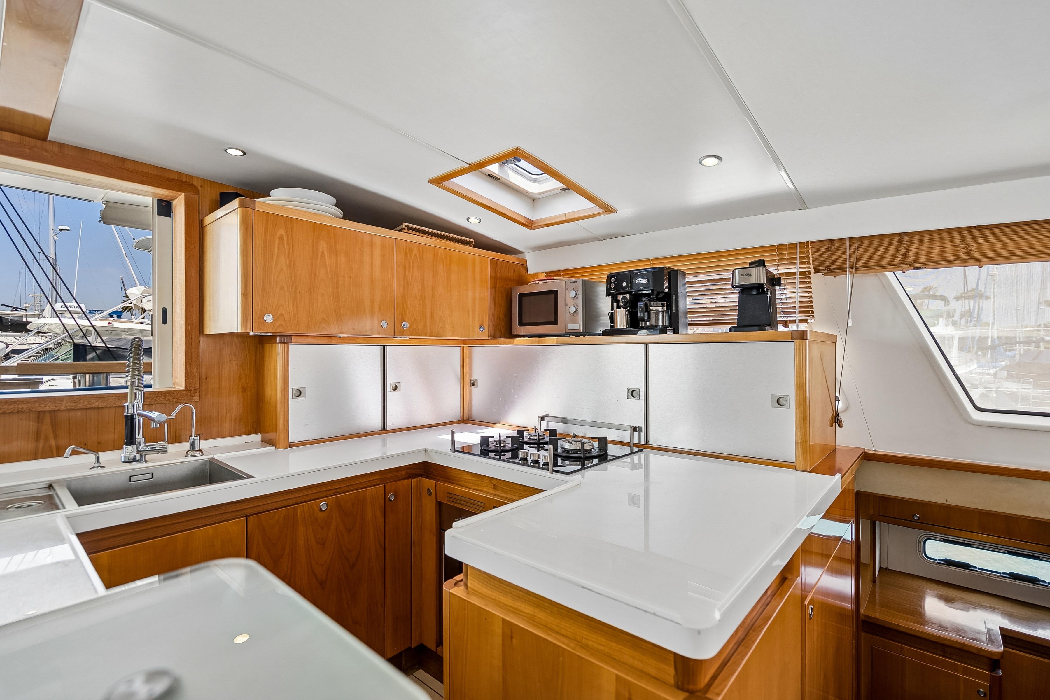 Luxurious Catana 65 yacht kitchen interior, featuring modern appliances and sleek wooden cabinetry, 2009 model.