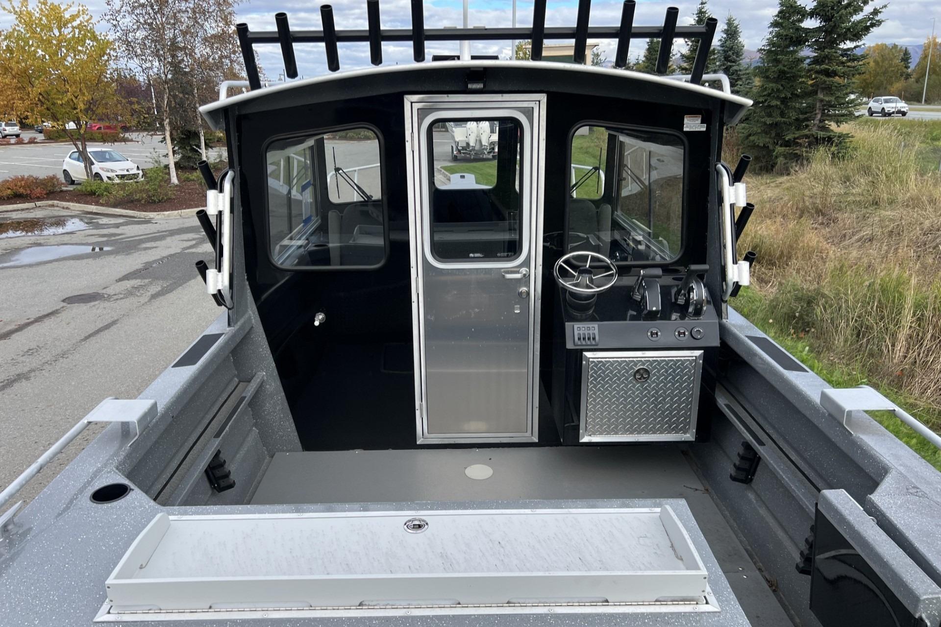 2024 Spartan 220 Maximus boat interior with steering console and storage, parked outdoors.