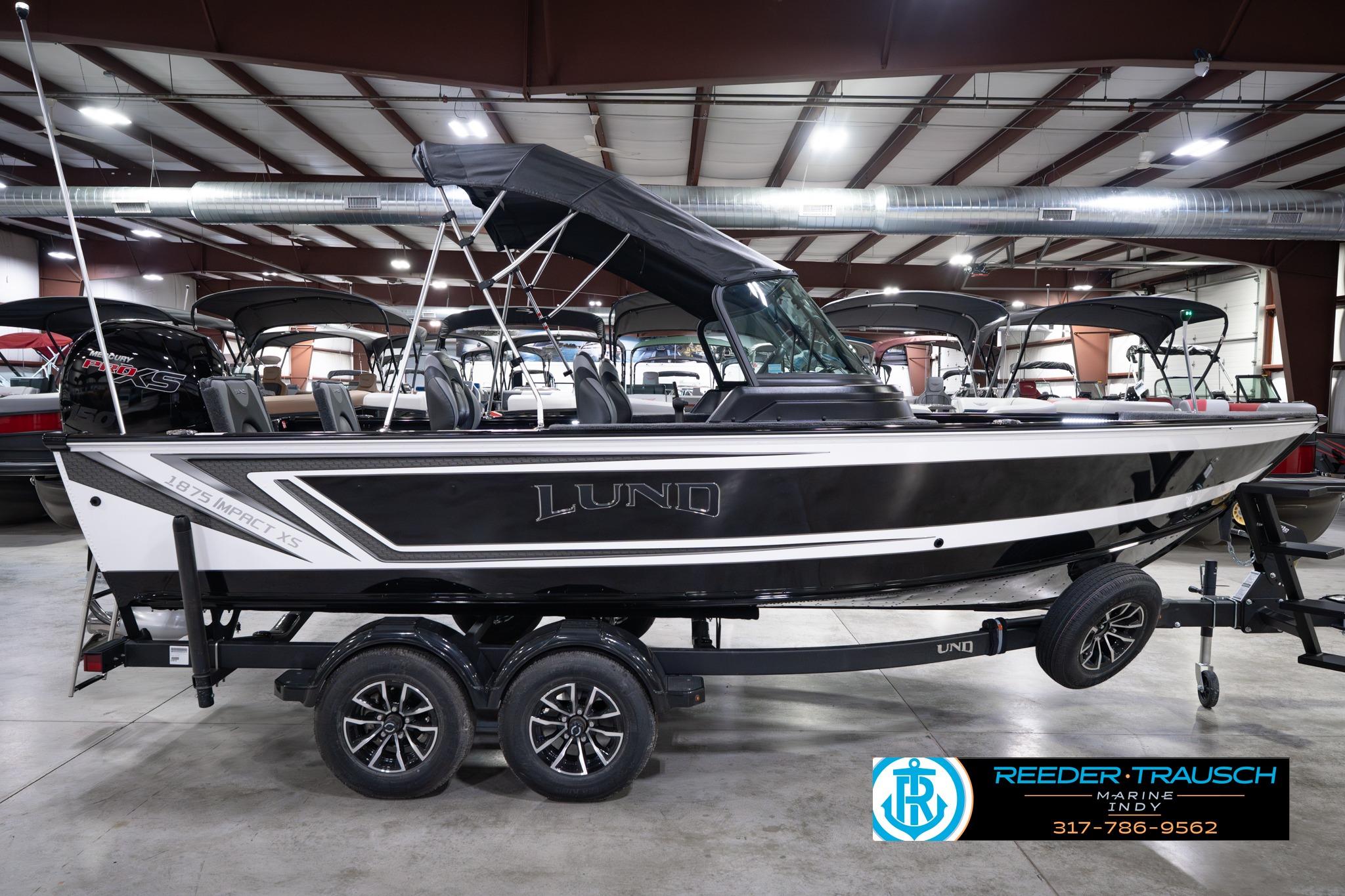 2026 Lund 1875 Impact XS SS boat in showroom, black and white design, on trailer.
