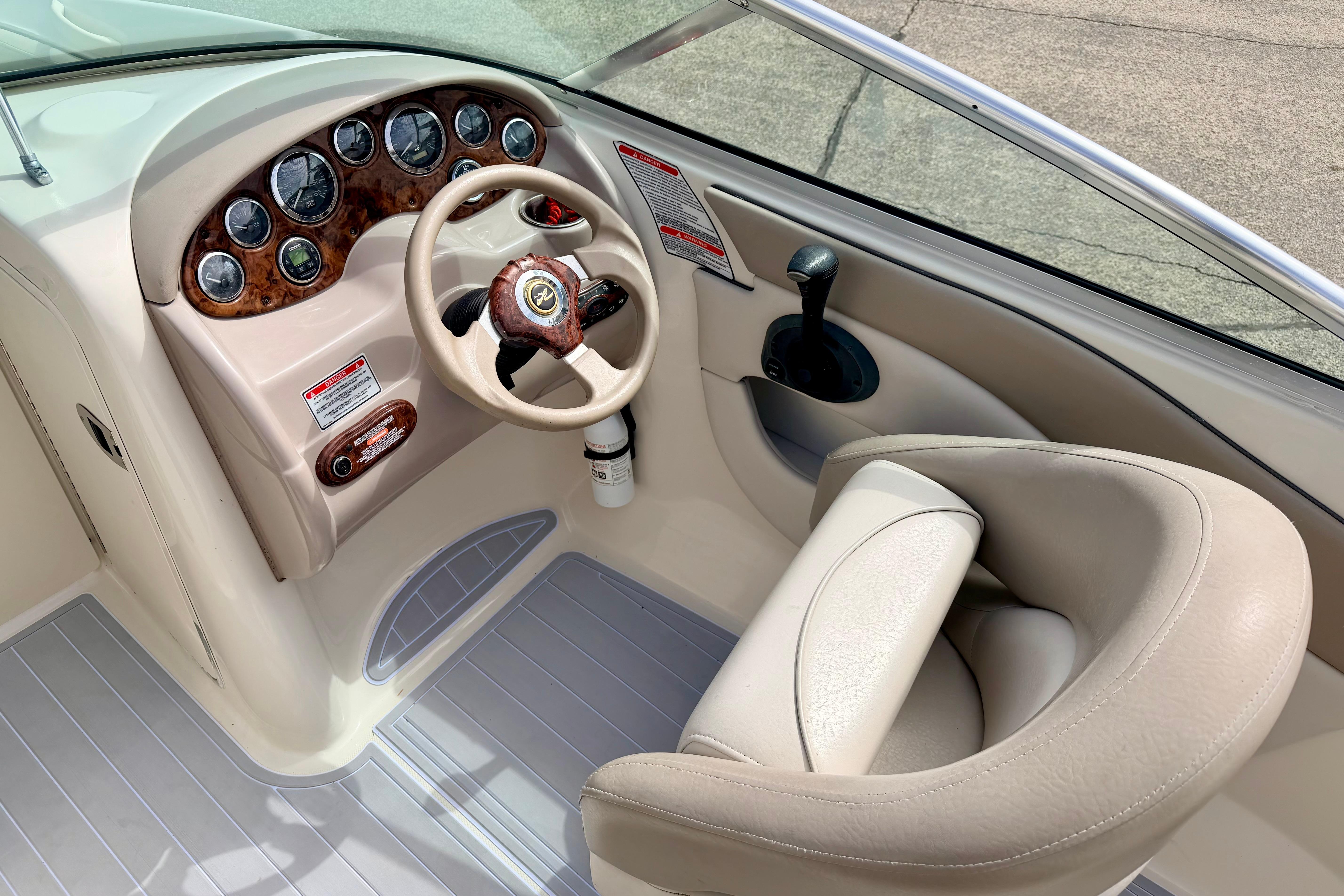 2003 Sea Ray 200 Sundeck helm with gauges, steering wheel, and beige seating.