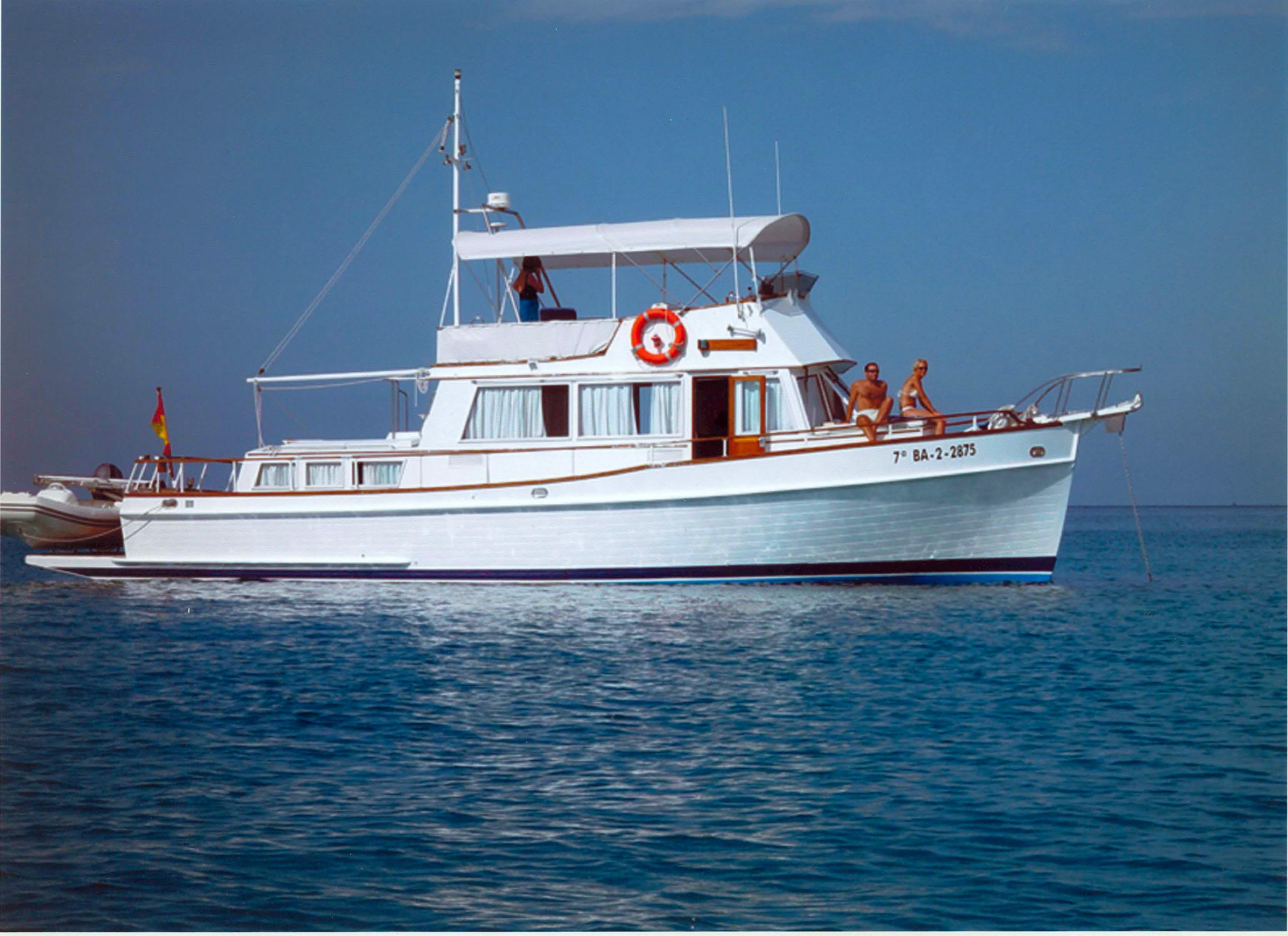 1980 Grand Banks 42 Classic yacht on calm blue water, featuring a white hull and upper deck.