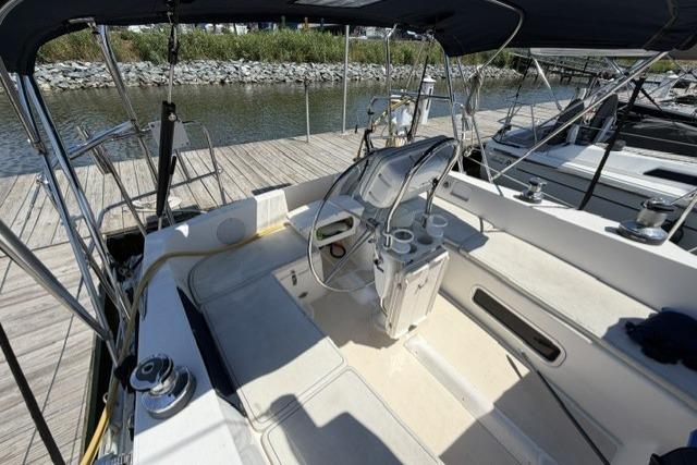 Cockpit of 2002 Saga 43 sailboat docked at marina, featuring steering wheel and seating area.