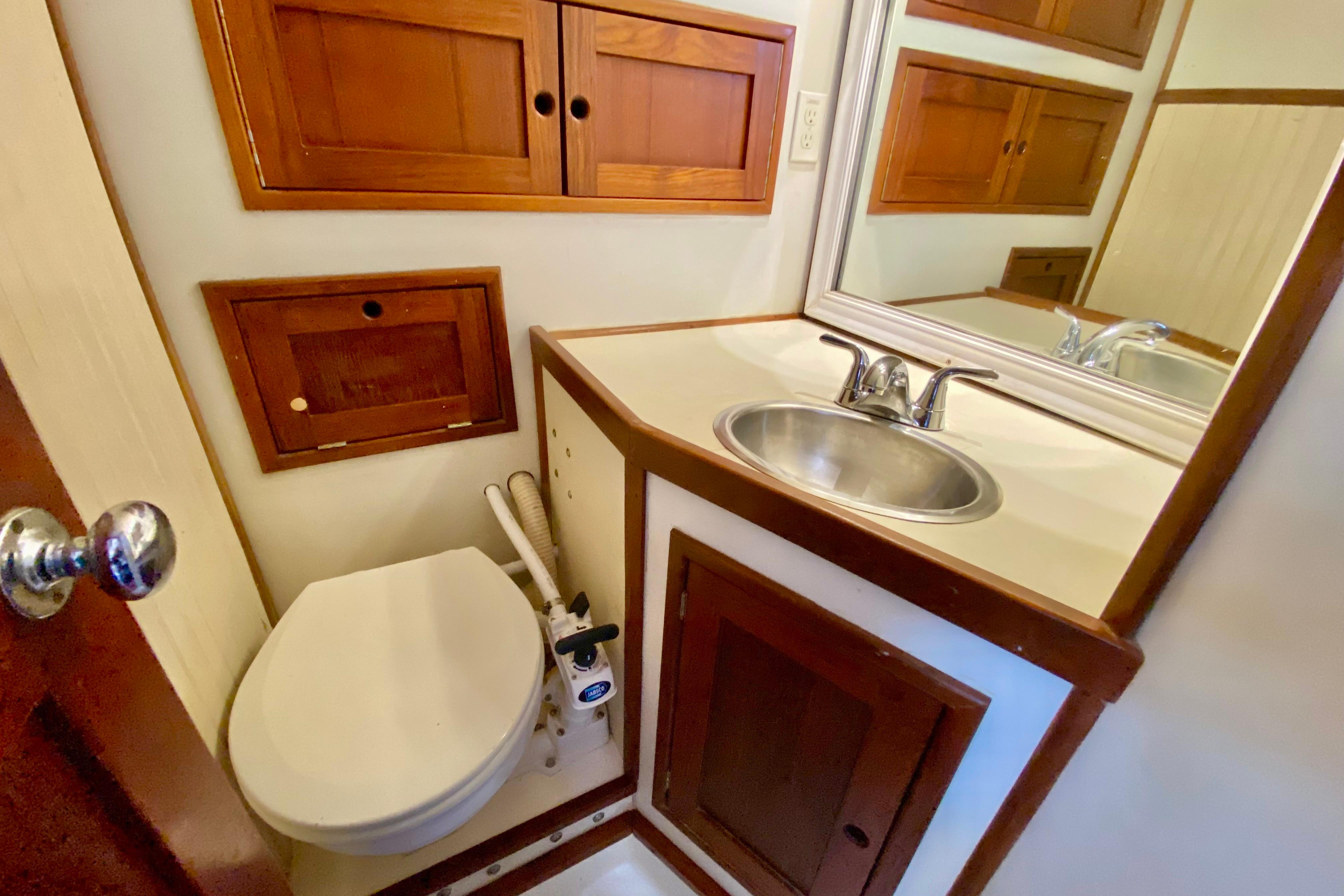 Compact bathroom in 1980 Wellington 44 yacht with wooden cabinets and stainless steel sink.