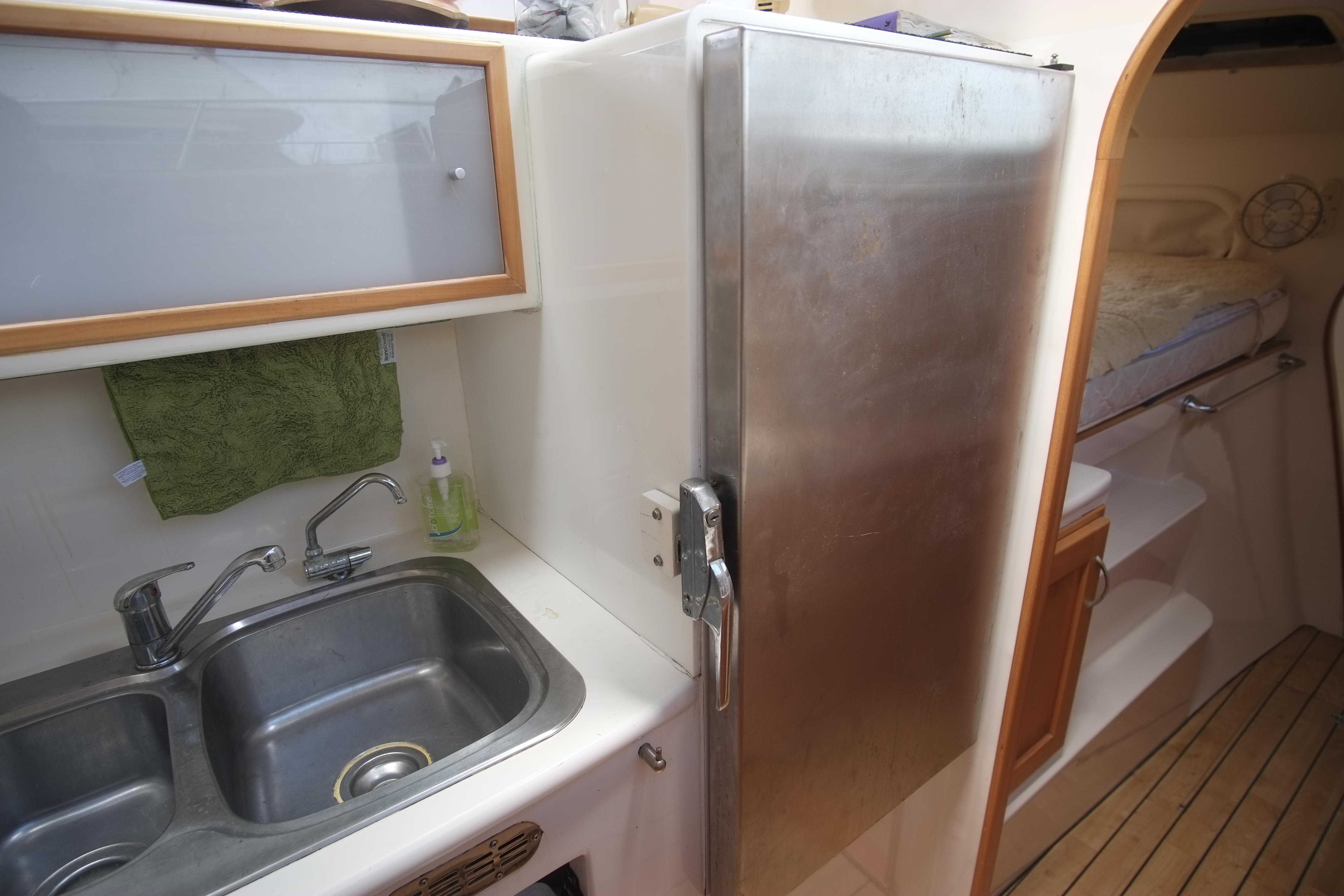 Compact kitchen area in a 2007 Lightwave 38 yacht with stainless steel sink and fridge.