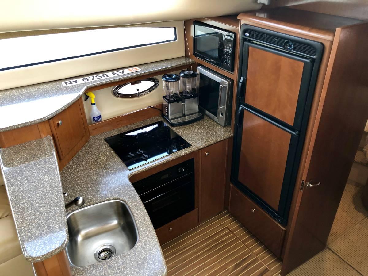 2005 Meridian 459 Motoryacht kitchen with sink, stove, microwave, and refrigerator.