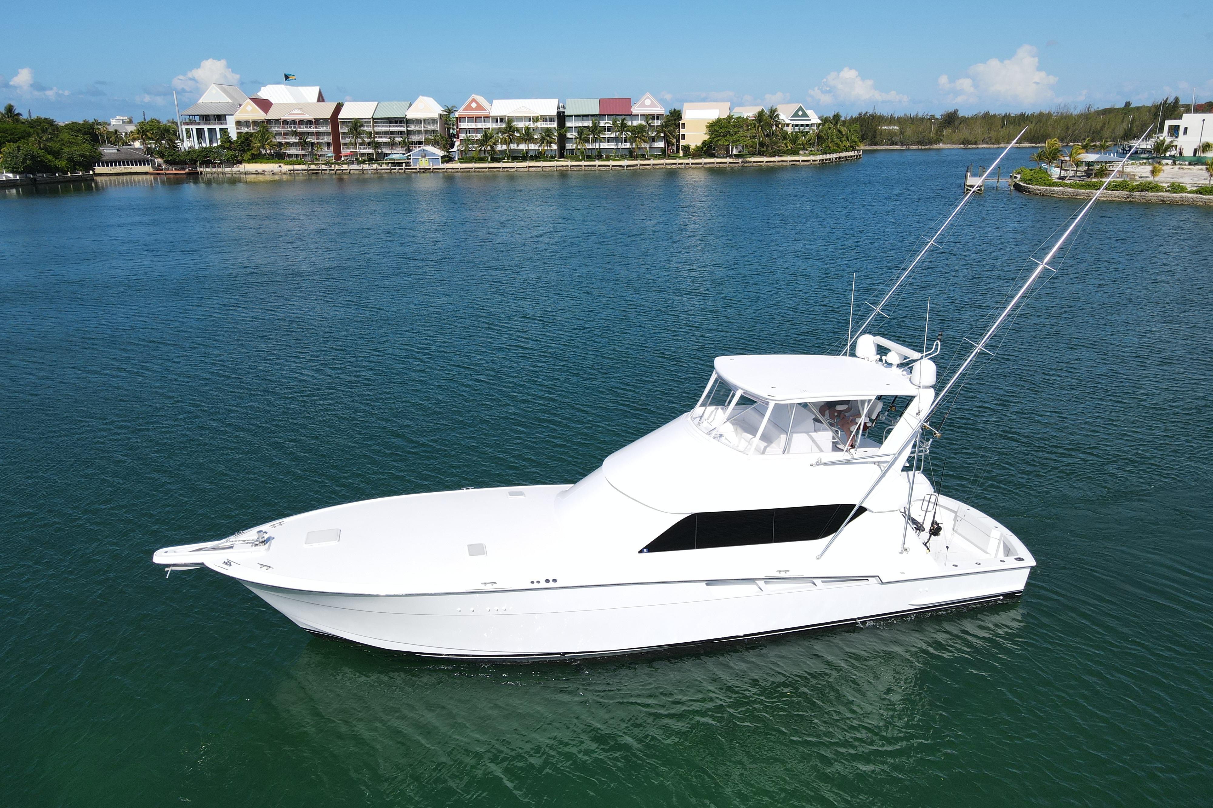 2004 Hatteras 60 Convertible yacht on calm water with scenic background.