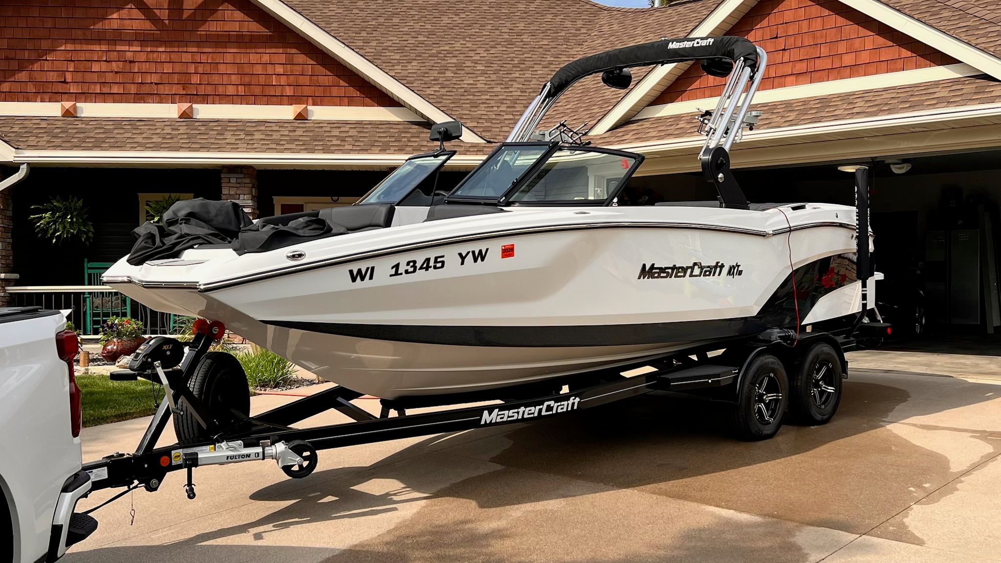 A white 2020 MasterCraft NXT22 boat on a trailer in front of a house.