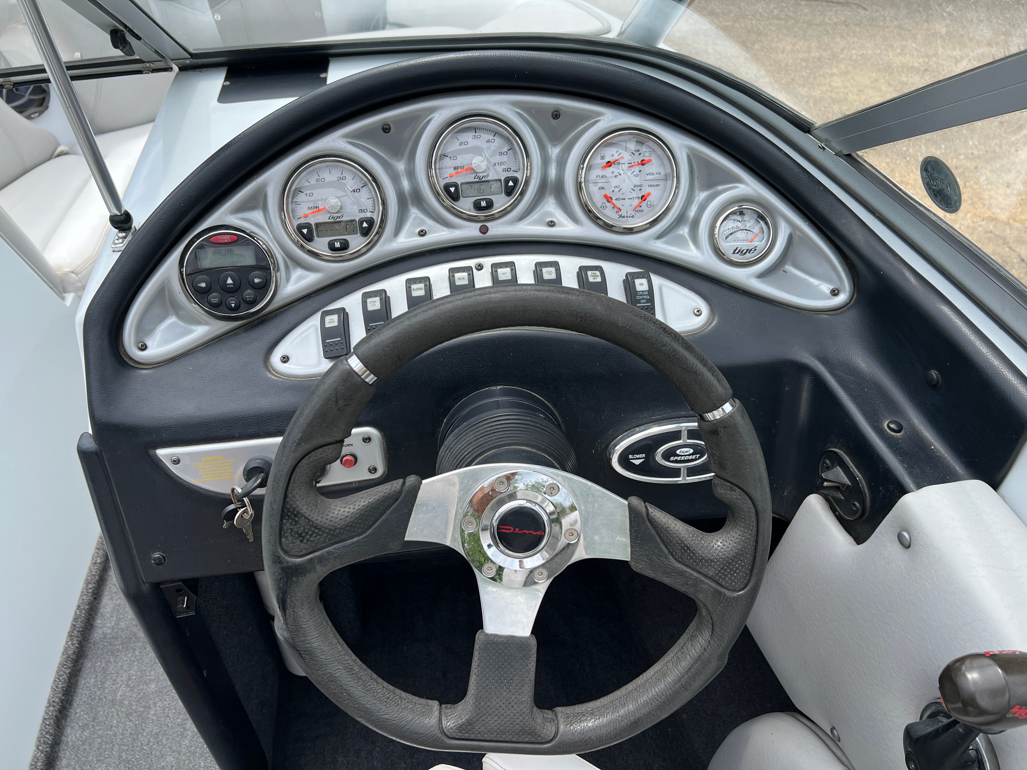 The image shows the dashboard of a 2006 Tigé 20i boat with multiple gauges and a steering wheel.