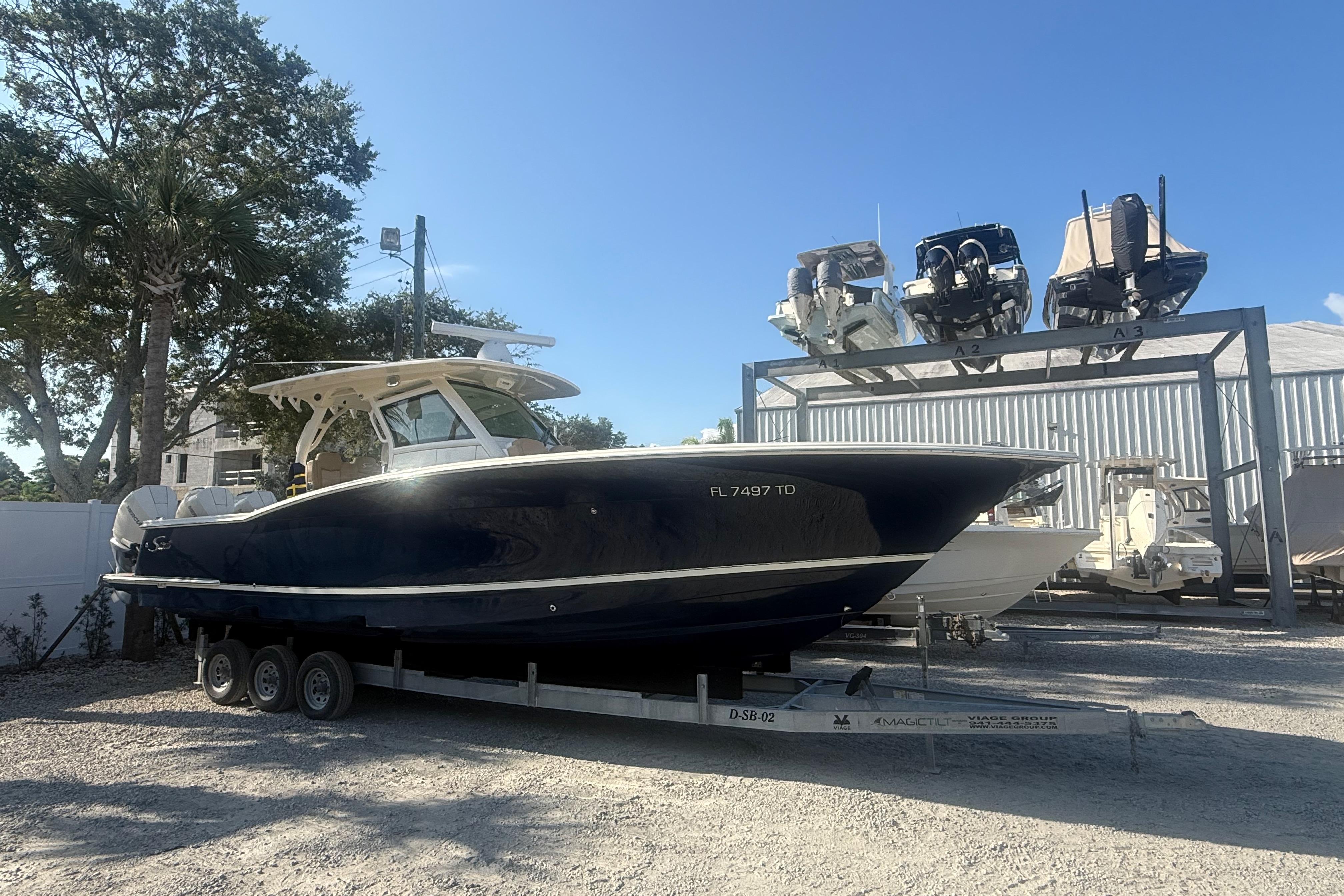 2022 Scout 355 LXF boat on trailer, parked outdoors under clear blue sky.