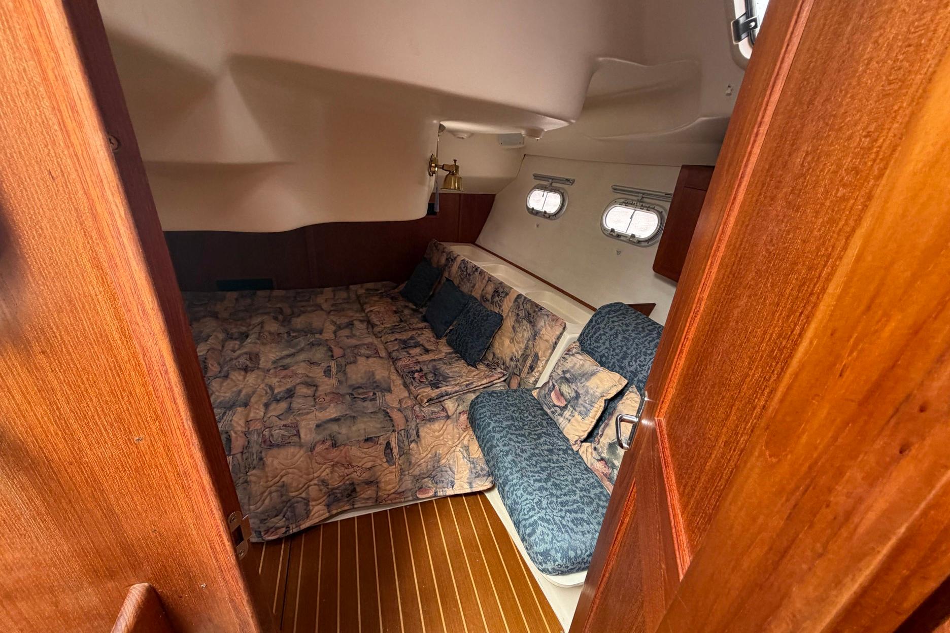 Cozy cabin interior of 1998 Hunter 410 sailboat with patterned bedding and wooden accents.