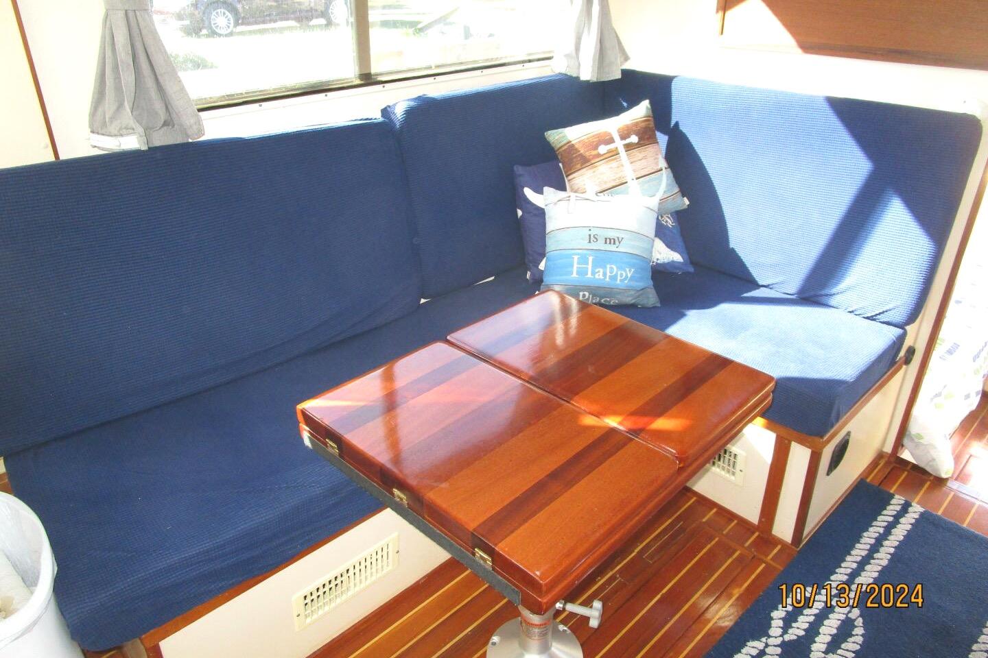Cozy interior of 1997 Rosborough Trawler with blue seating and wooden table.