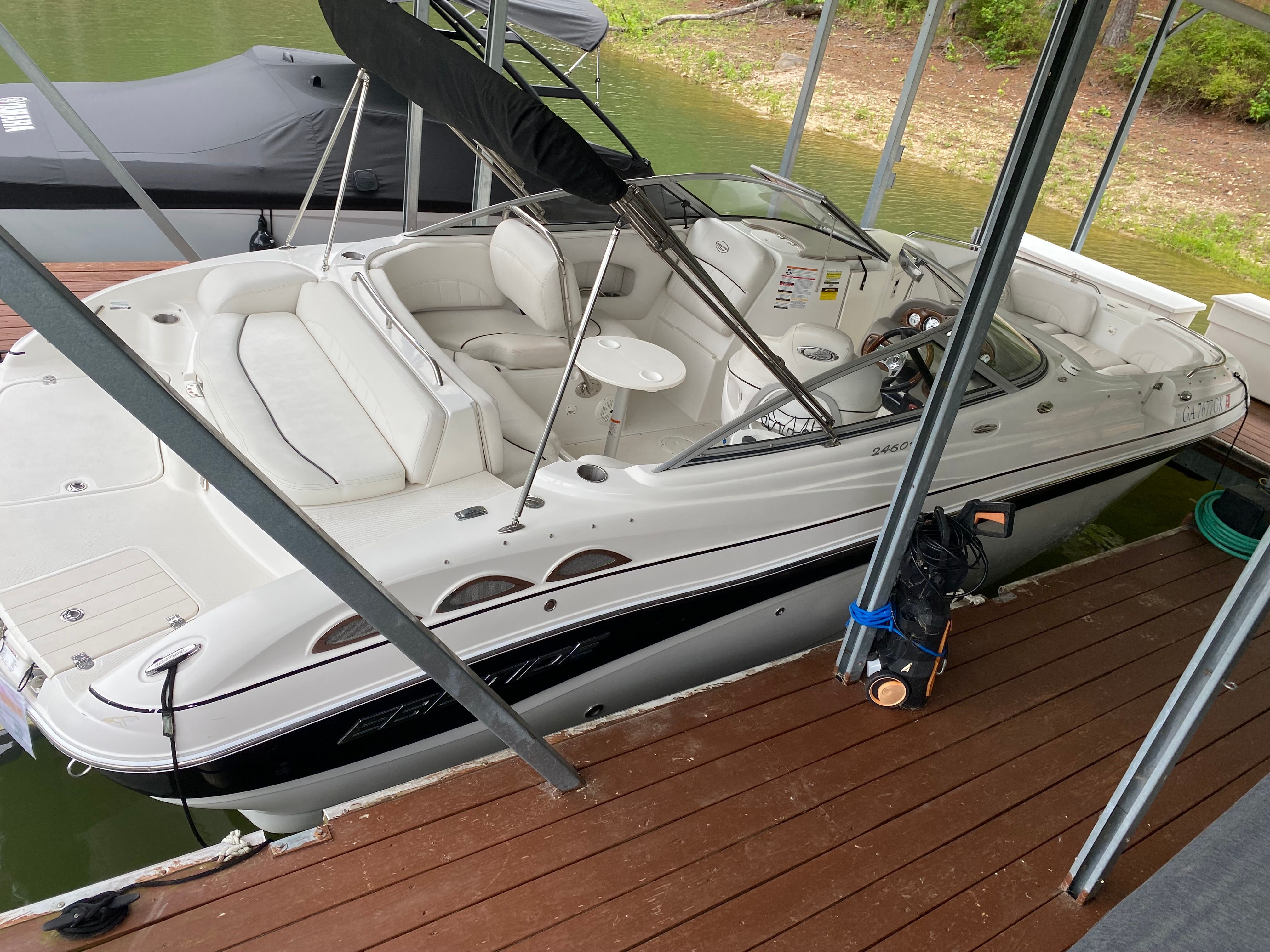 A white 2007 Ebbtide 2460 Z-Trak boat docked at a wooden pier in a covered area.