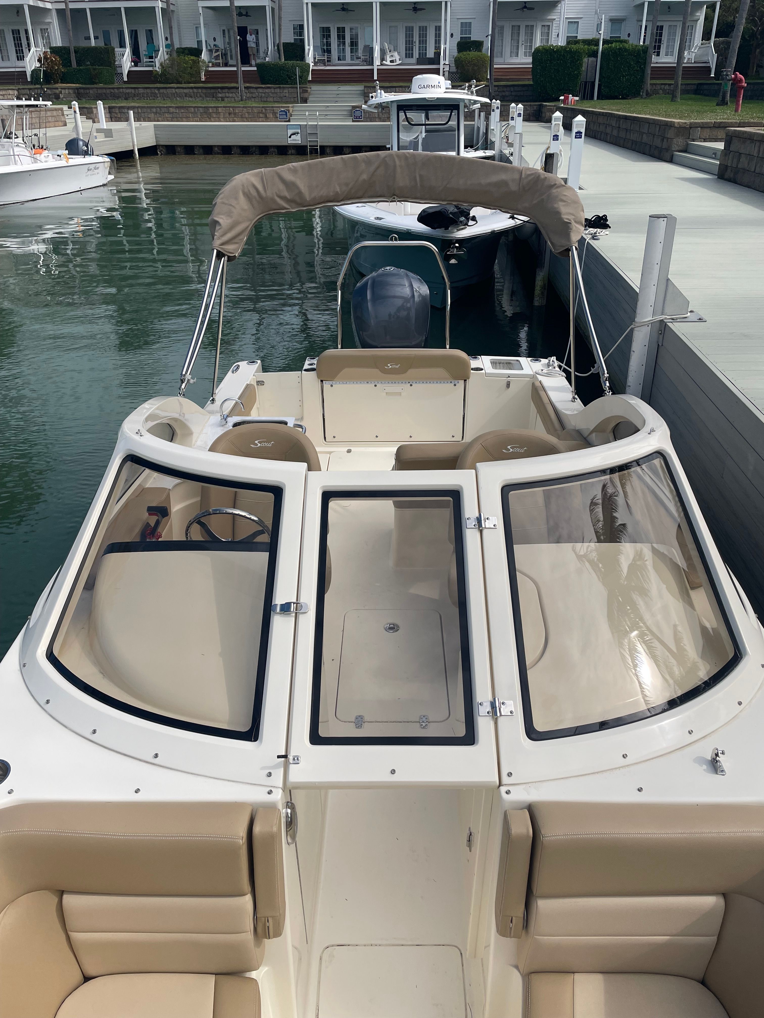 A 2020 Scout 235 Dorado boat docked. It features beige upholstery and a Bimini top.