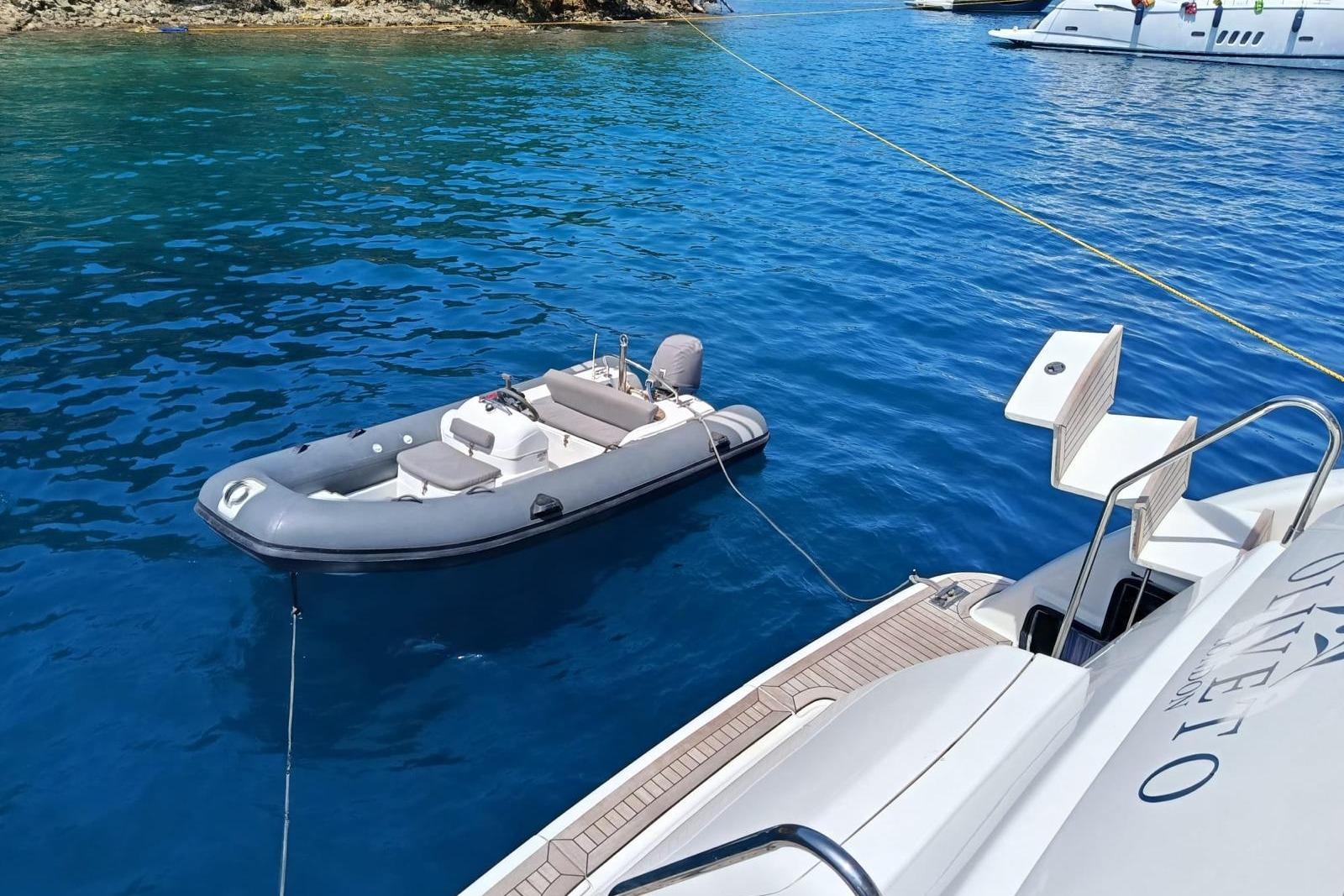Azimut 70 yacht from 2000 with a small boat in clear blue water.