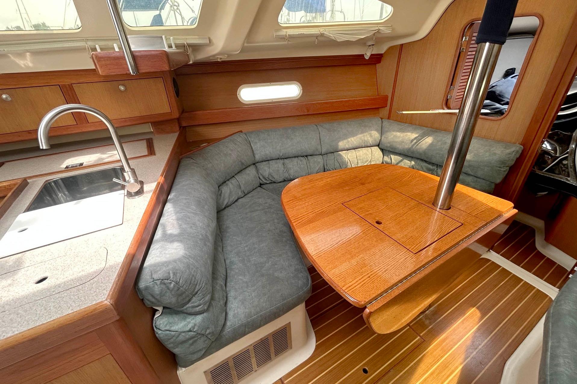 Cozy interior of a 1998 Hunter 340 sailboat with a wooden dining area and kitchenette.